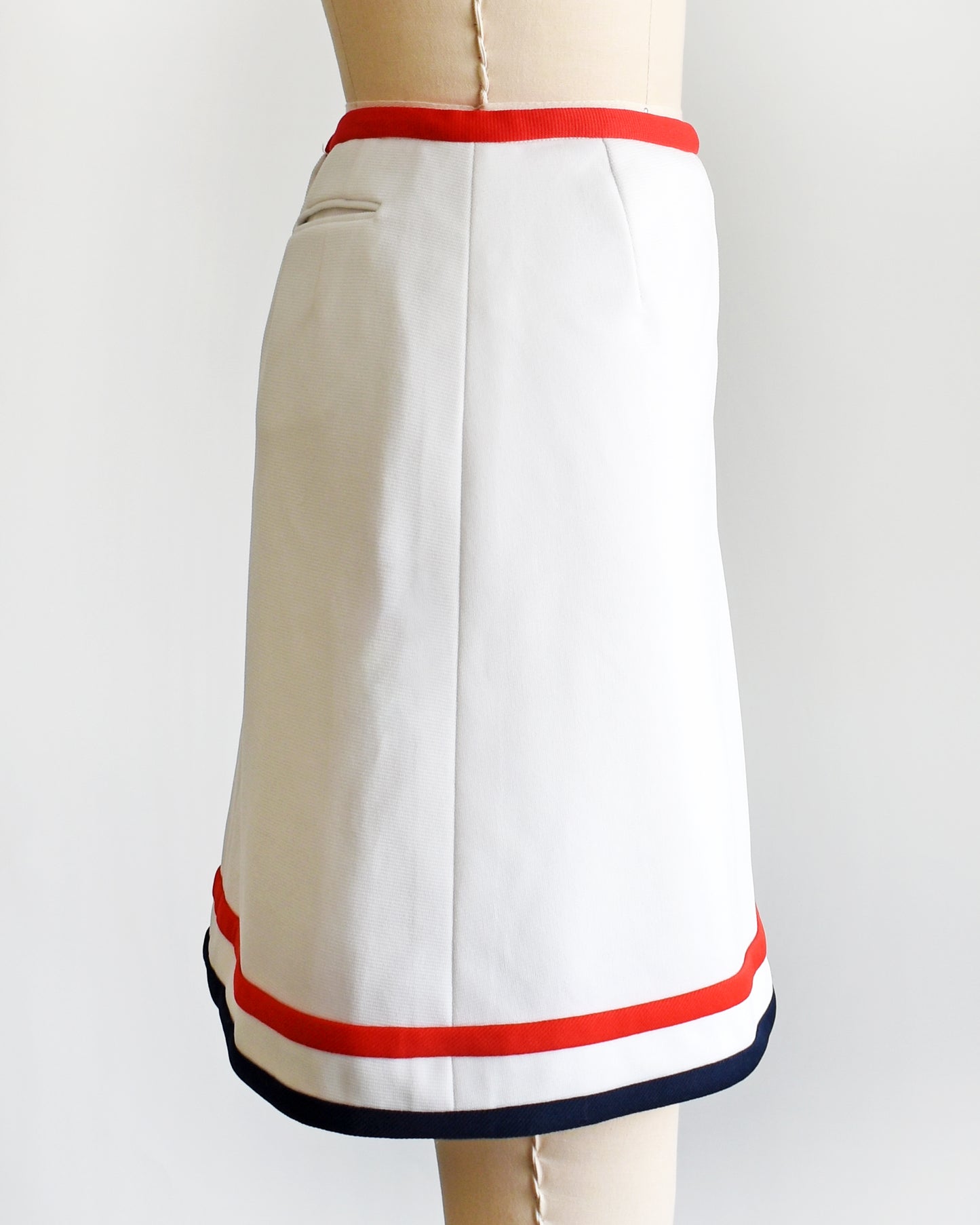 side view of a vintage 1970s white skort with red and navy trim on a dress form against a white background