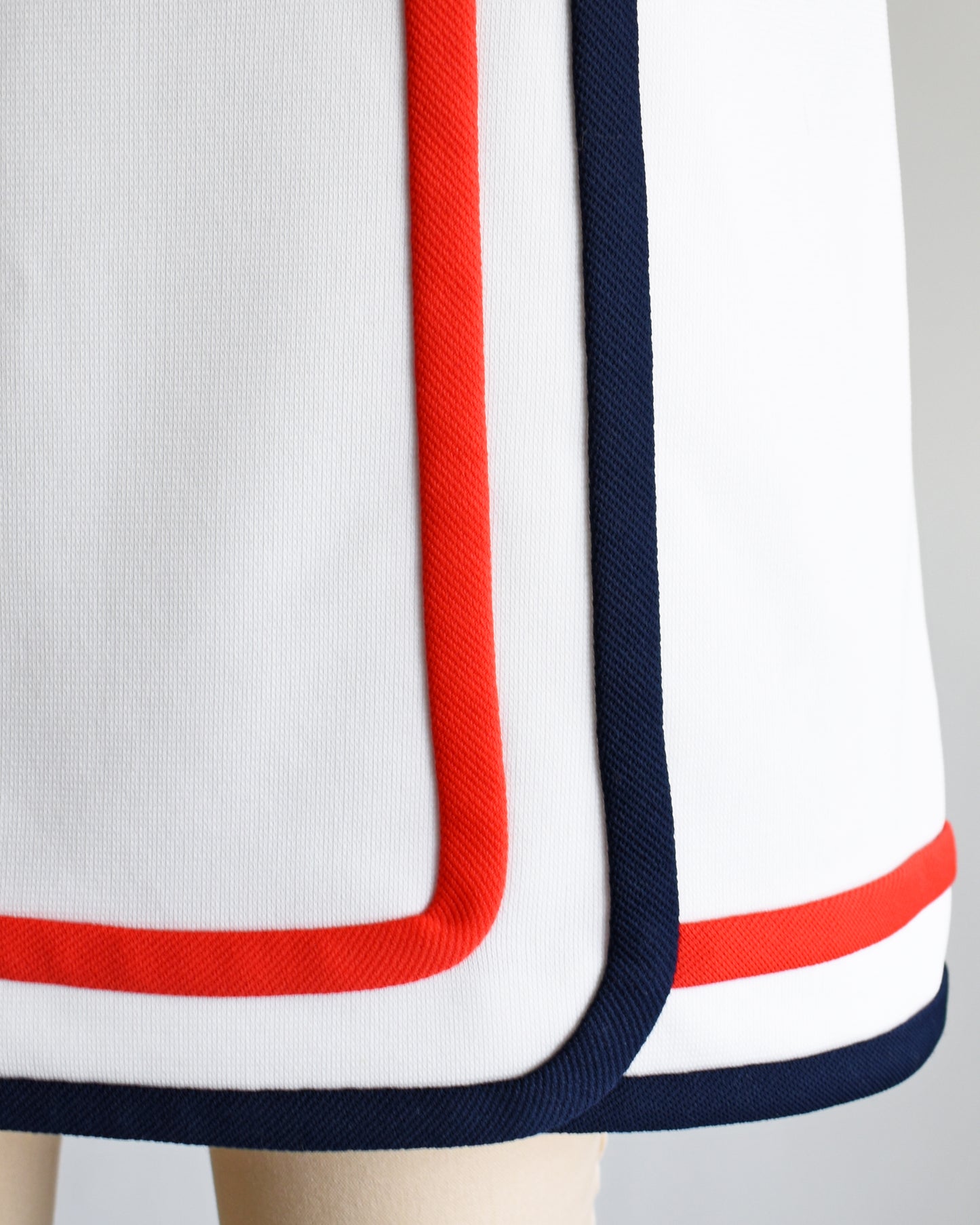 close up of a vintage 1970s white skort with red and navy trim on a dress form against a white background