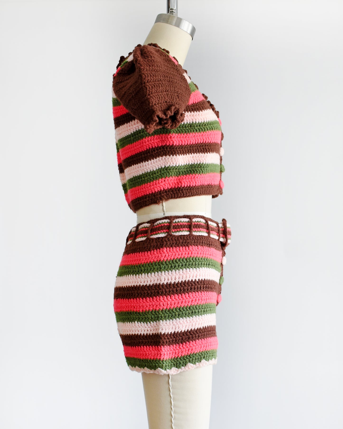 side view of a vintage 1970s striped knit crop top and hot pant shorts on a mannequin against a white background