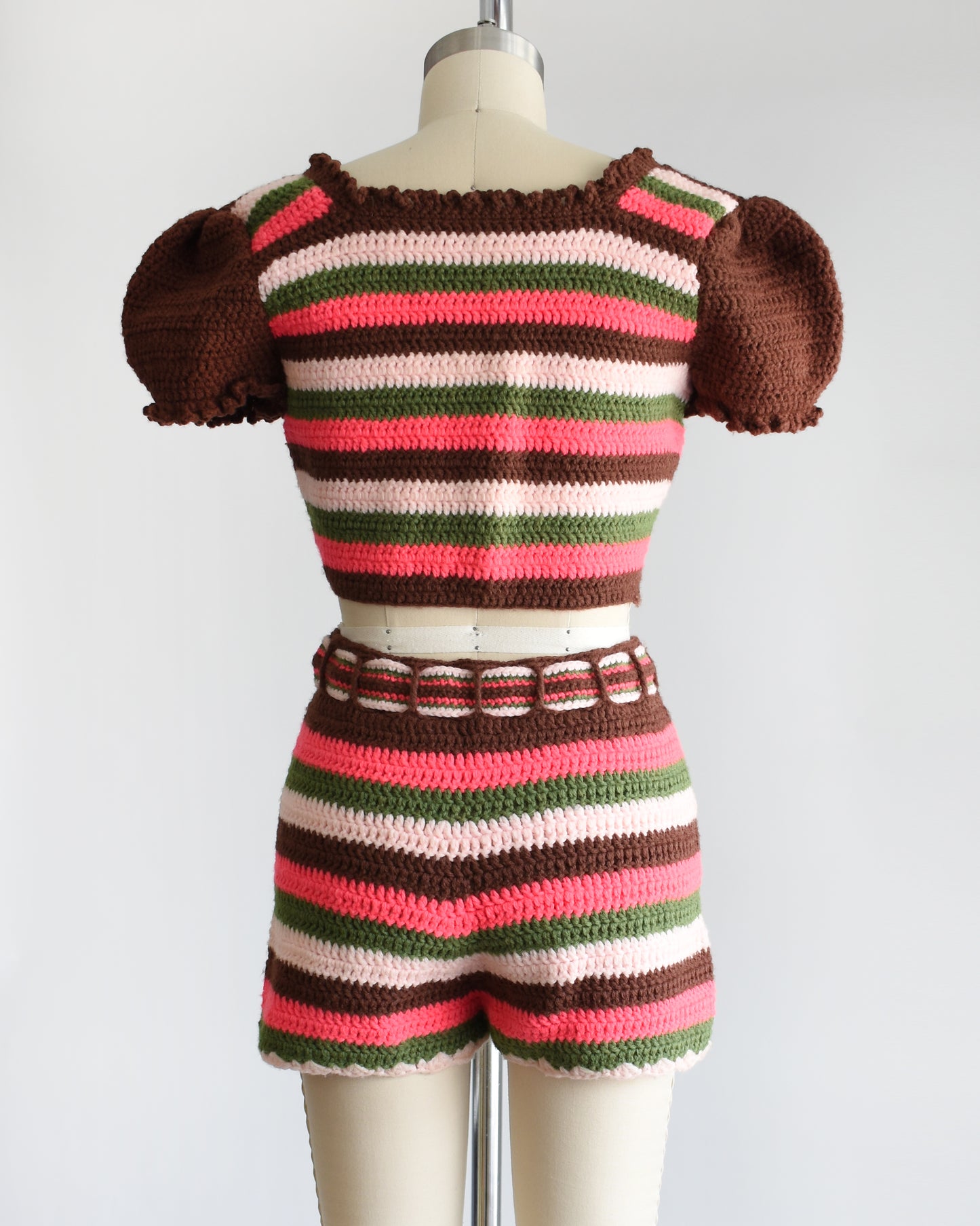 back view of a vintage 1970s striped knit crop top and hot pant shorts on a mannequin against a white background