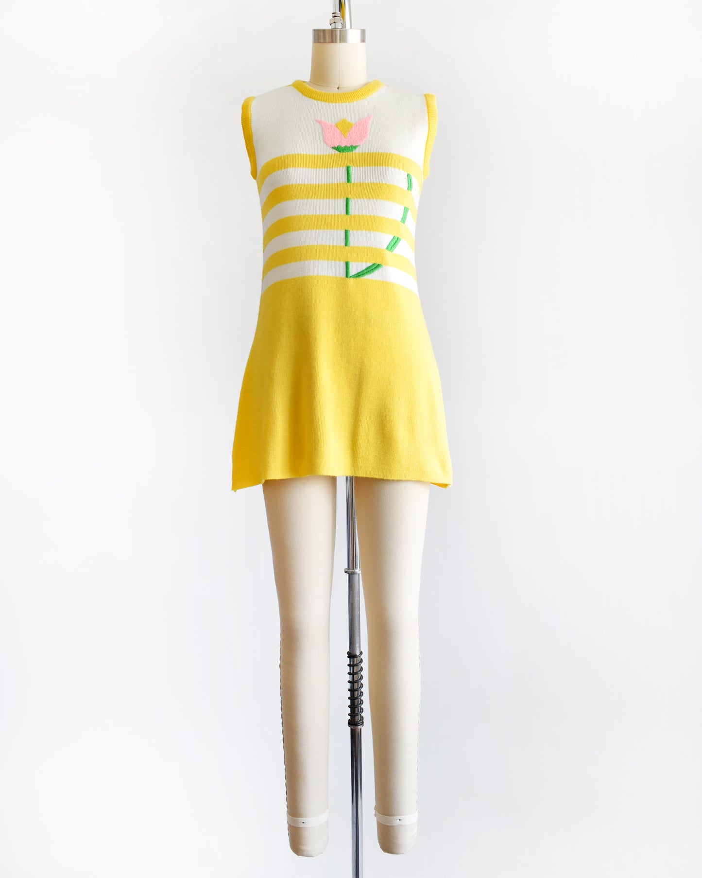 A vintage 1970s yellow dress with floral design on a mannequin against a white background