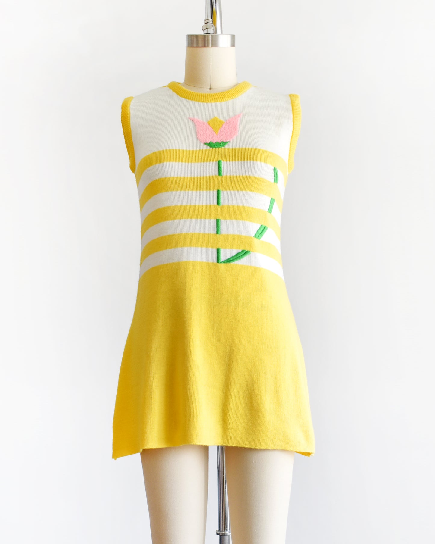 A vintage 1970s yellow dress with floral design on a mannequin against a white background