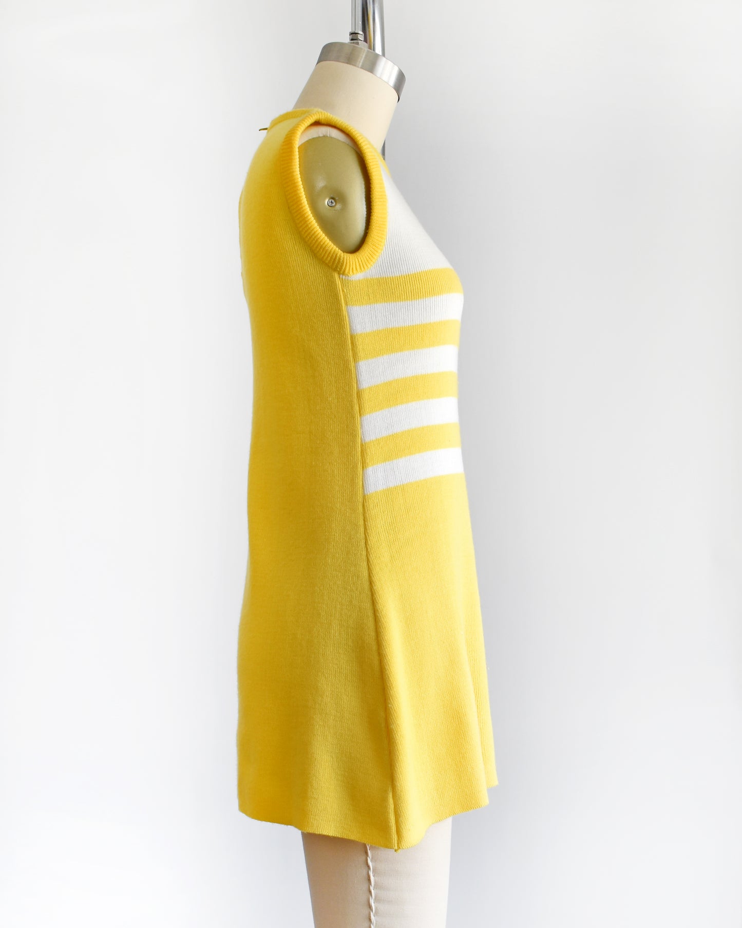 side view of a vintage 1970s yellow dress with floral design on a mannequin against a white background