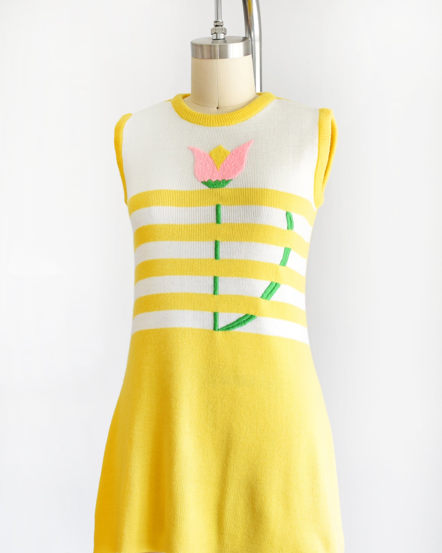 side front view of a vintage 1970s yellow dress with floral design on a mannequin against a white background