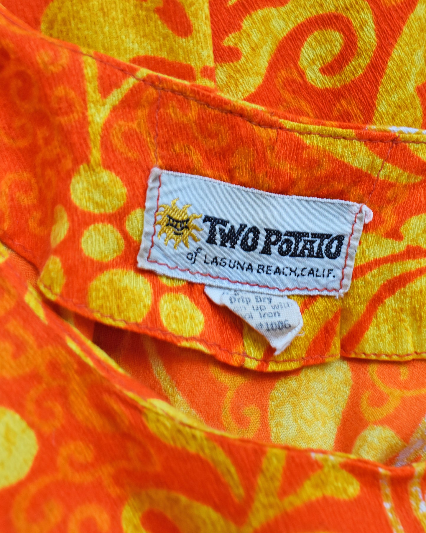 Close-up of a Two Potato label on an orange and yellow floral maxi dress