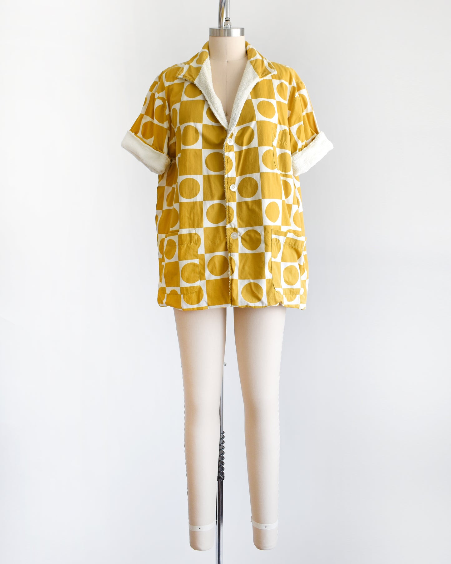 a vintage 1960s mustard yellow patterned cabana shirt with white terry clothing lining on a mannequin against a white background