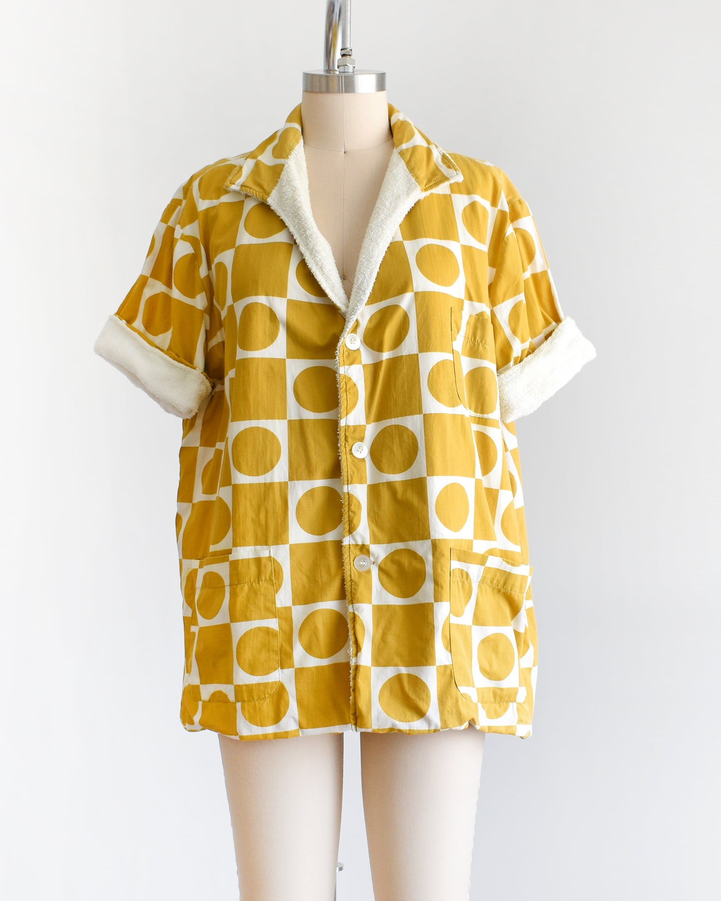 a vintage 1960s mustard yellow patterned cabana shirt with white terry clothing lining on a mannequin against a white background