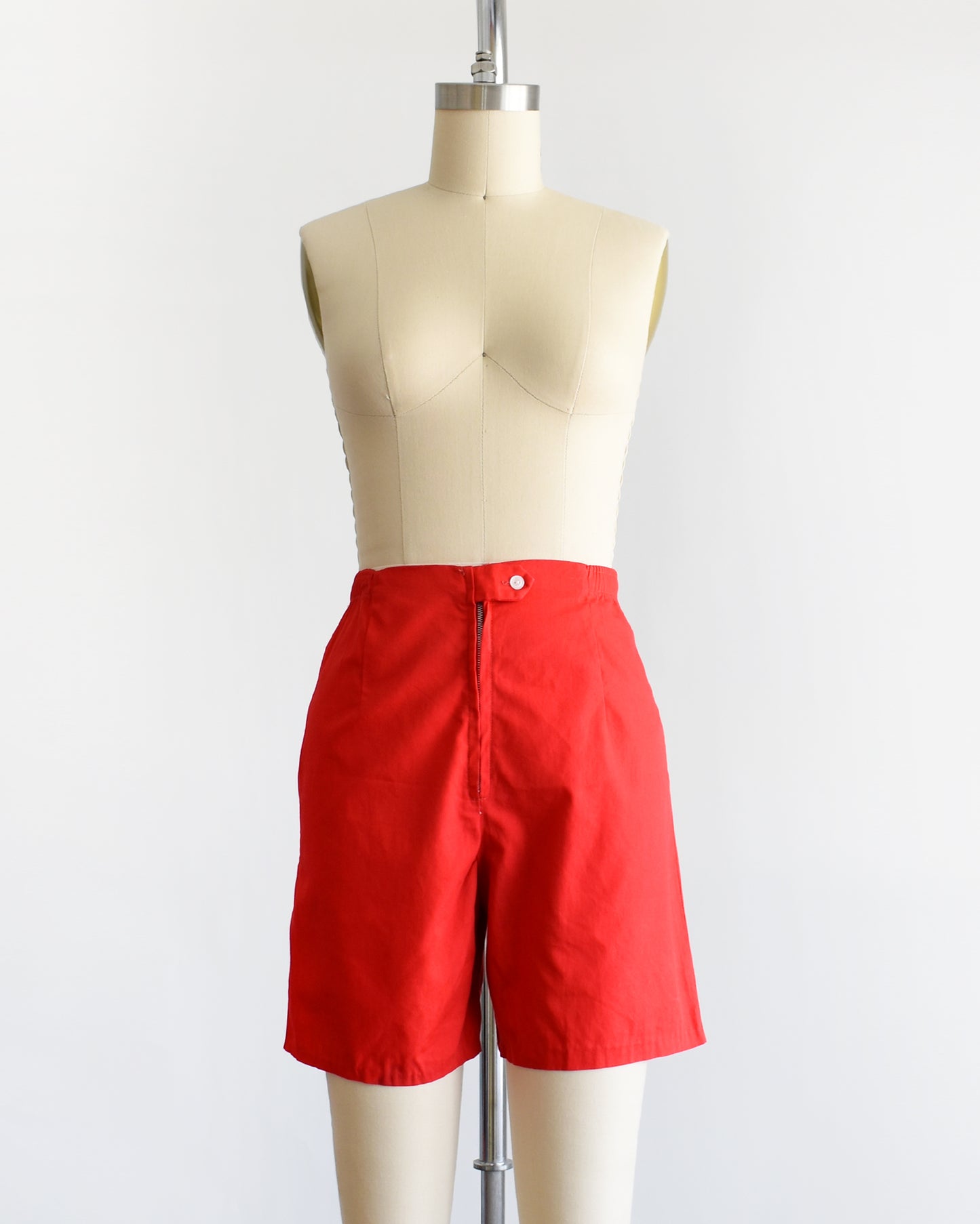 a pair of vintage 1960s red shorts on a mannequin against a white background