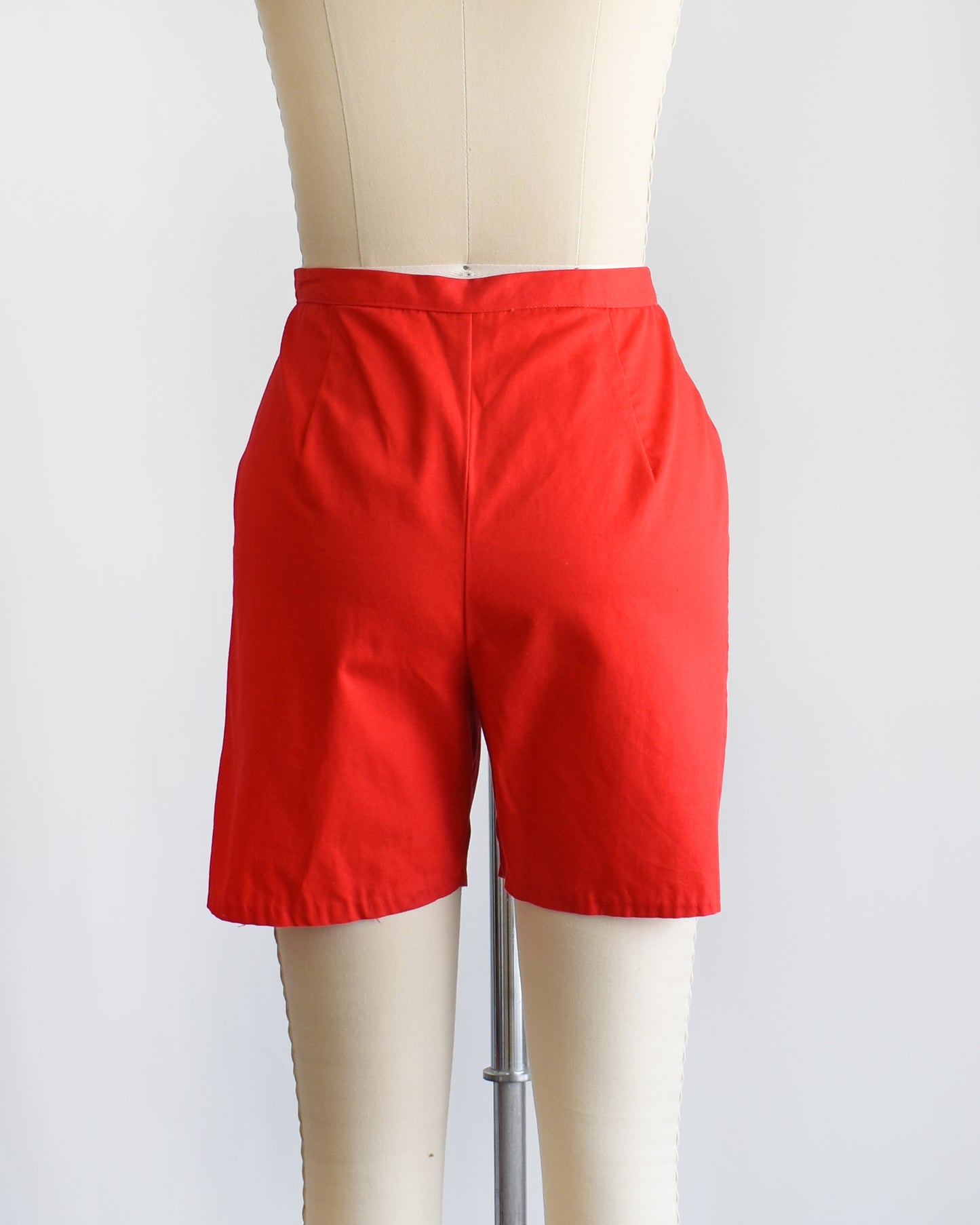 back view of a pair of vintage 1960s red shorts on a mannequin against a white background