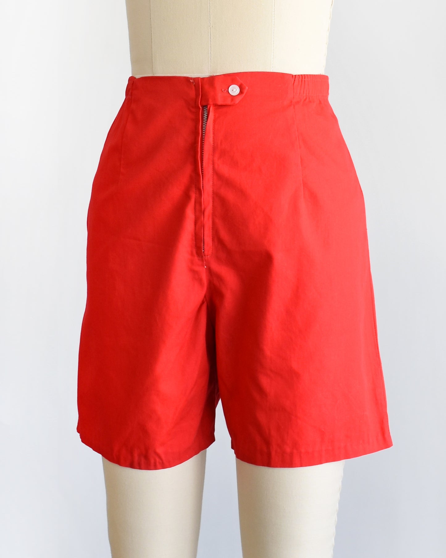 side front view of a pair of vintage 1960s red shorts on a mannequin against a white background