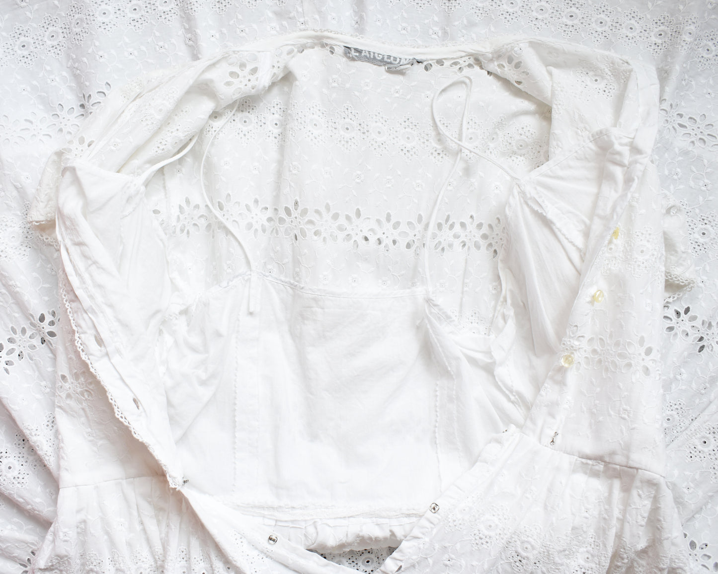 close up of the bodice of a vintage 1960s L’Aiglon eyelet white dress which is open and shows the lined bodie