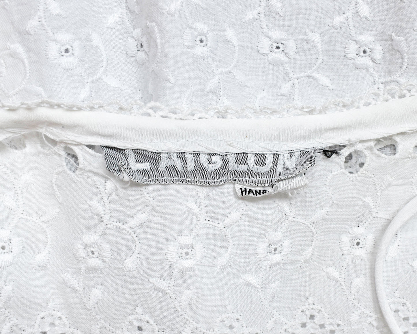 Close-up of a white lace dres which shows the 'L' Aiglon' tag