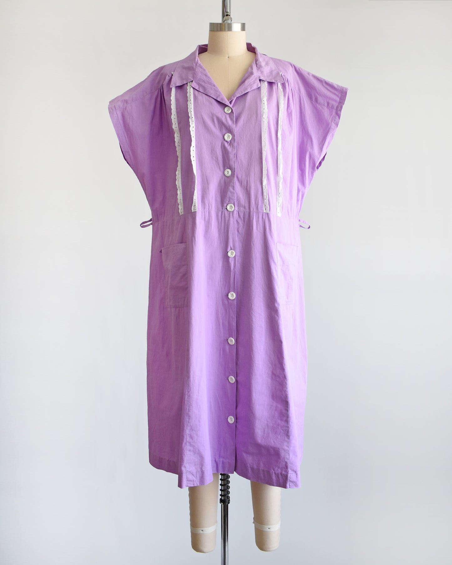 a vintage 1950s purple dress by Fruit of the Loom on a mannequin against a white background