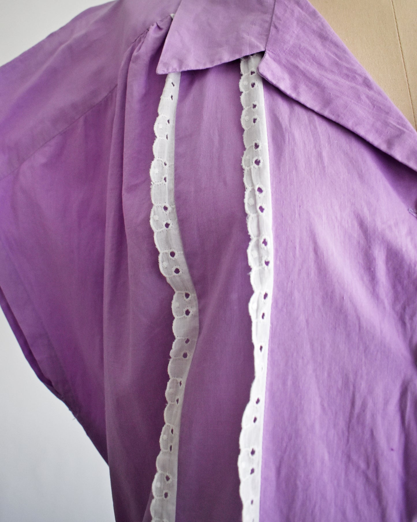 close up of the white lace trim on a vintage 1950s purple dress by Fruit of the Loom on a mannequin against a white background