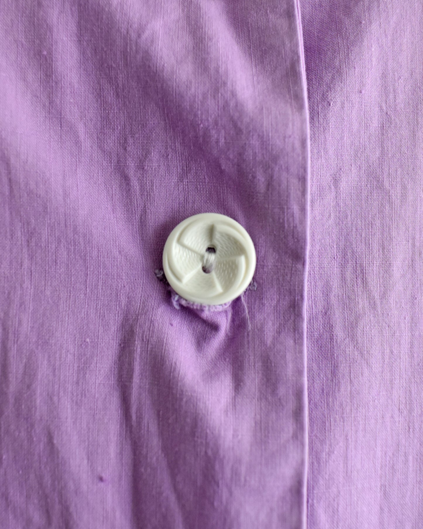 Close-up of a white button on a vintage 1950s purple dress by Fruit of the Loom