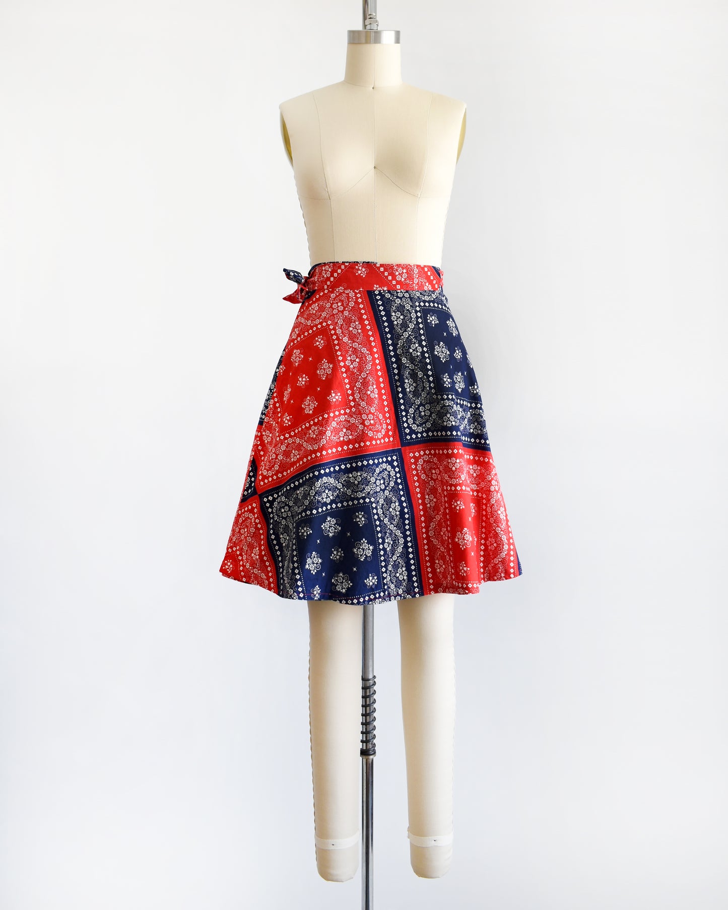 a vintage 1970s red and blue bandana patterned skirt on a mannequin against a white background