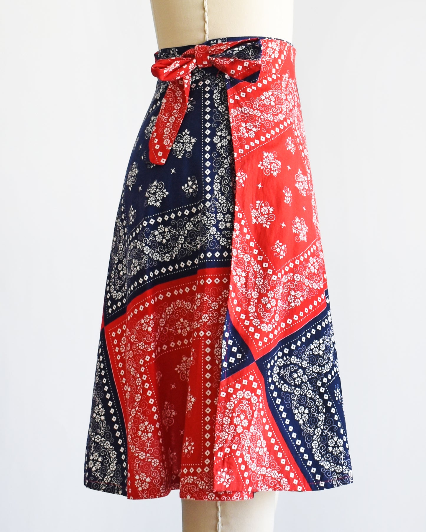 side view of a vintage 1970s red and blue bandana patterned skirt on a mannequin against a white background