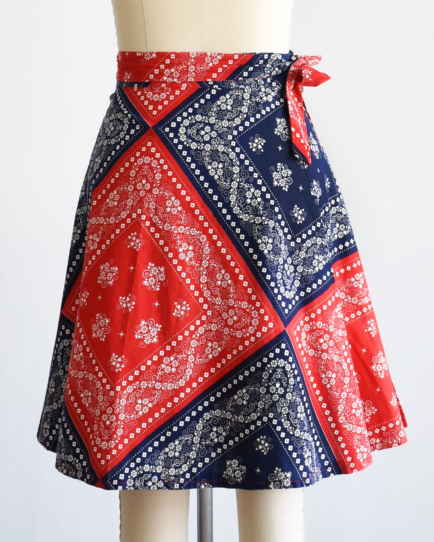 back view of a vintage 1970s red and blue bandana patterned skirt on a mannequin against a white background.