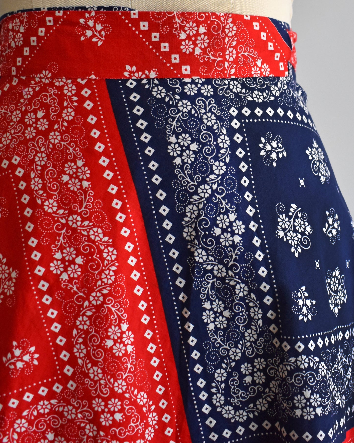 close up of a vintage 1970s red and blue bandana patterned skirt on a mannequin against a white background