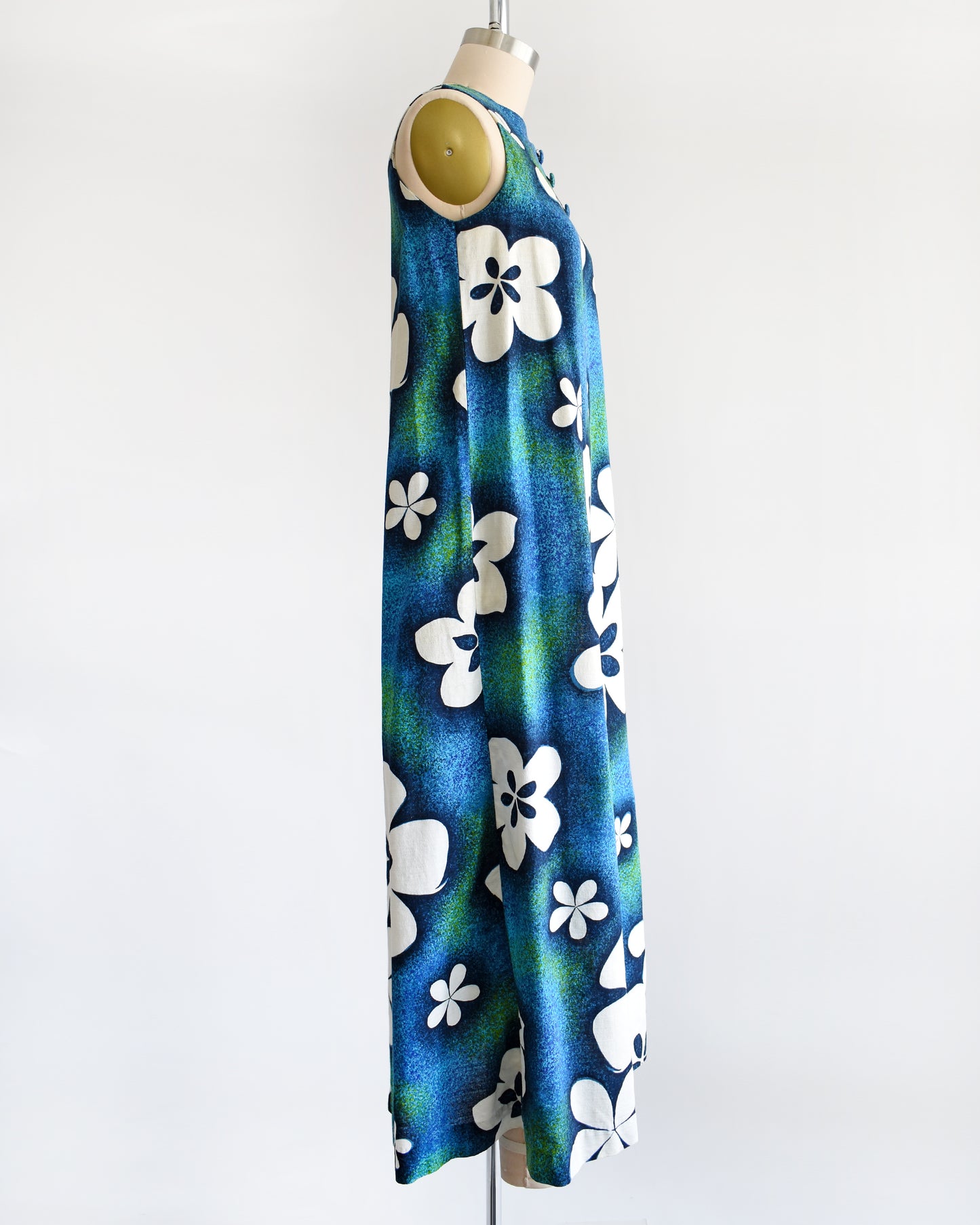 side view of a vintage 1970s blue and green Hawaiian maxi dress with white floral print