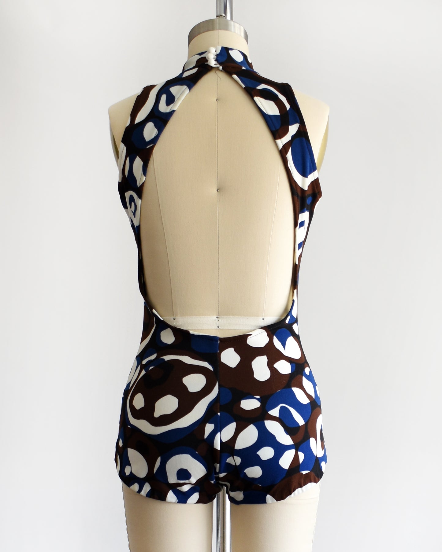 back view of a vintage 1960s psychedelic swimsuit on a mannequin against a white background
