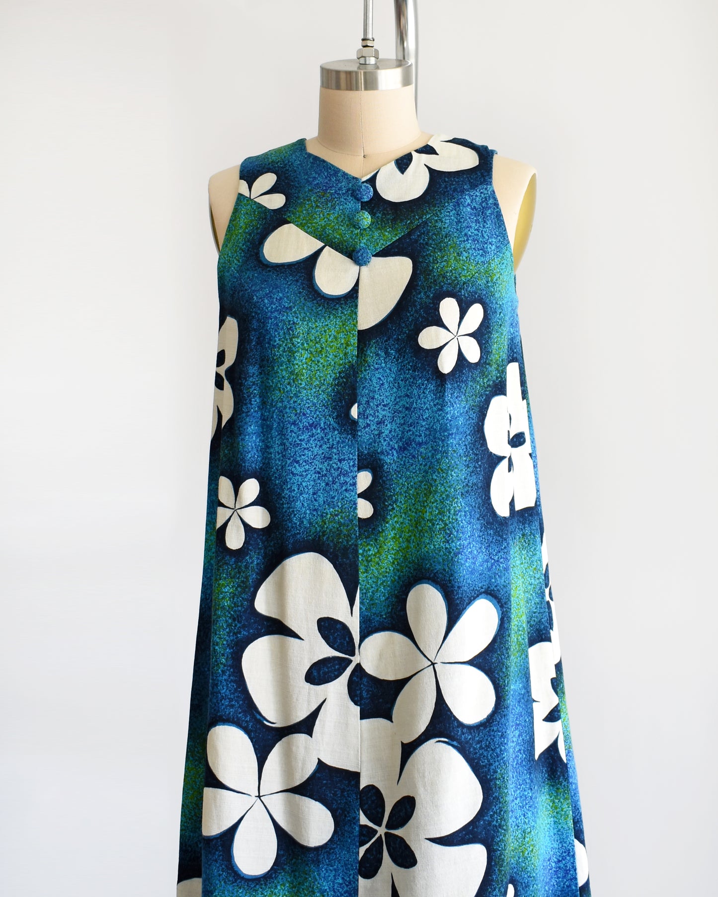 side front view of a vintage 1970s blue and green Hawaiian maxi dress with white floral print