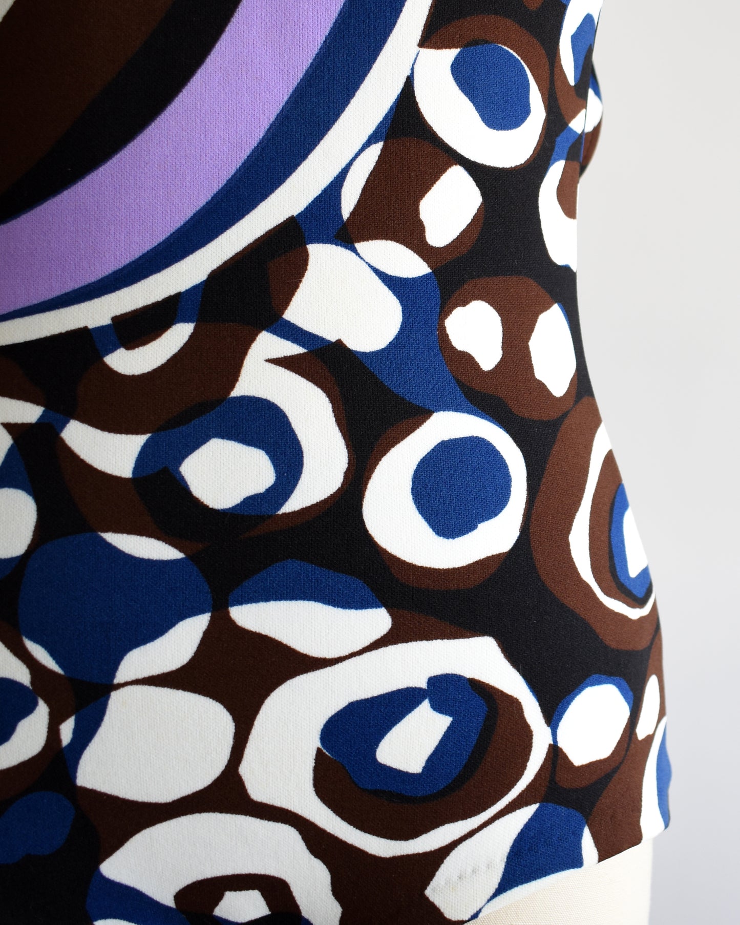 Close-up of a fabric with a pattern of blue, brown, and white circles on a plain background.