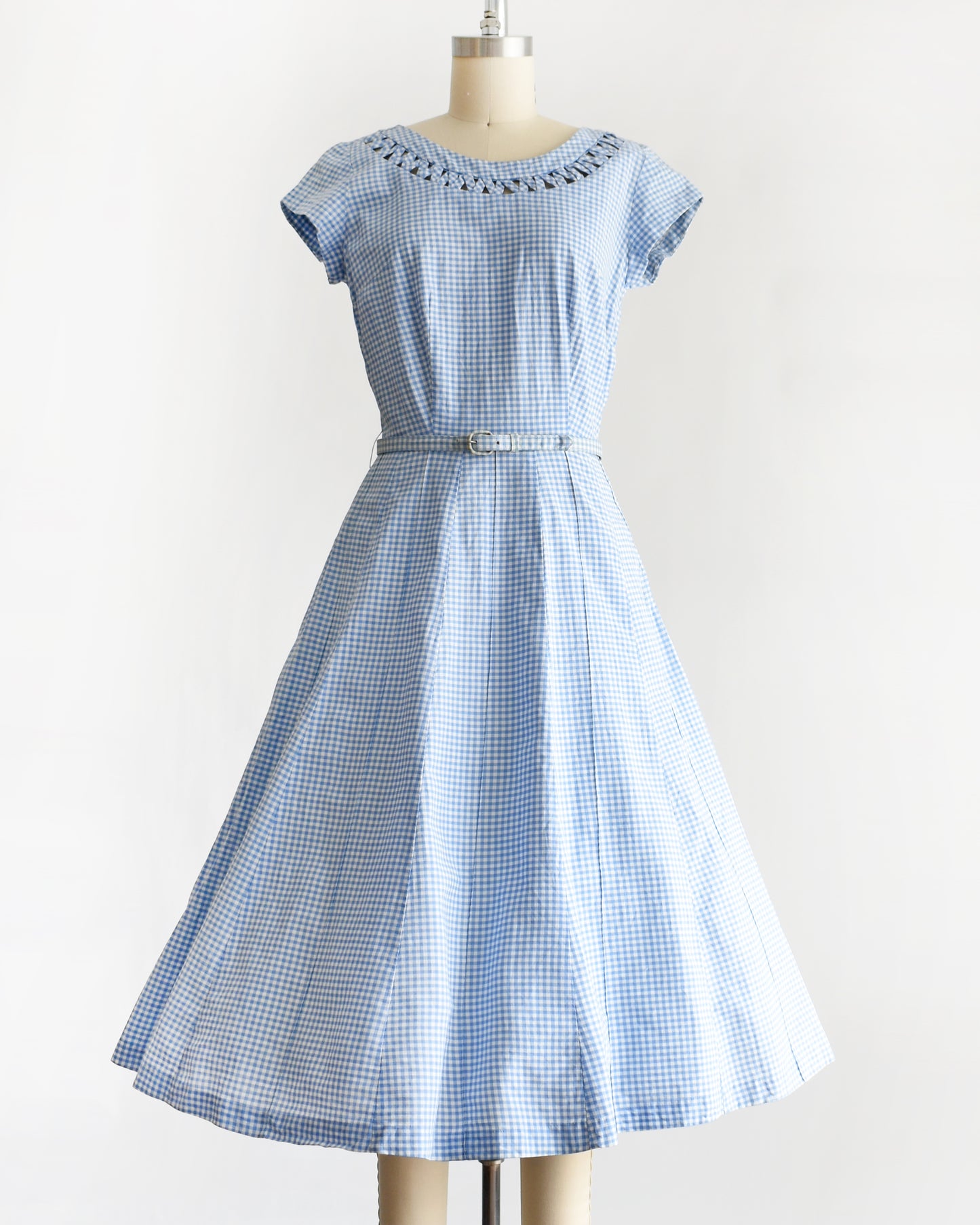 a vintage 1950s blue and white gingham dress on a mannequin against a white background