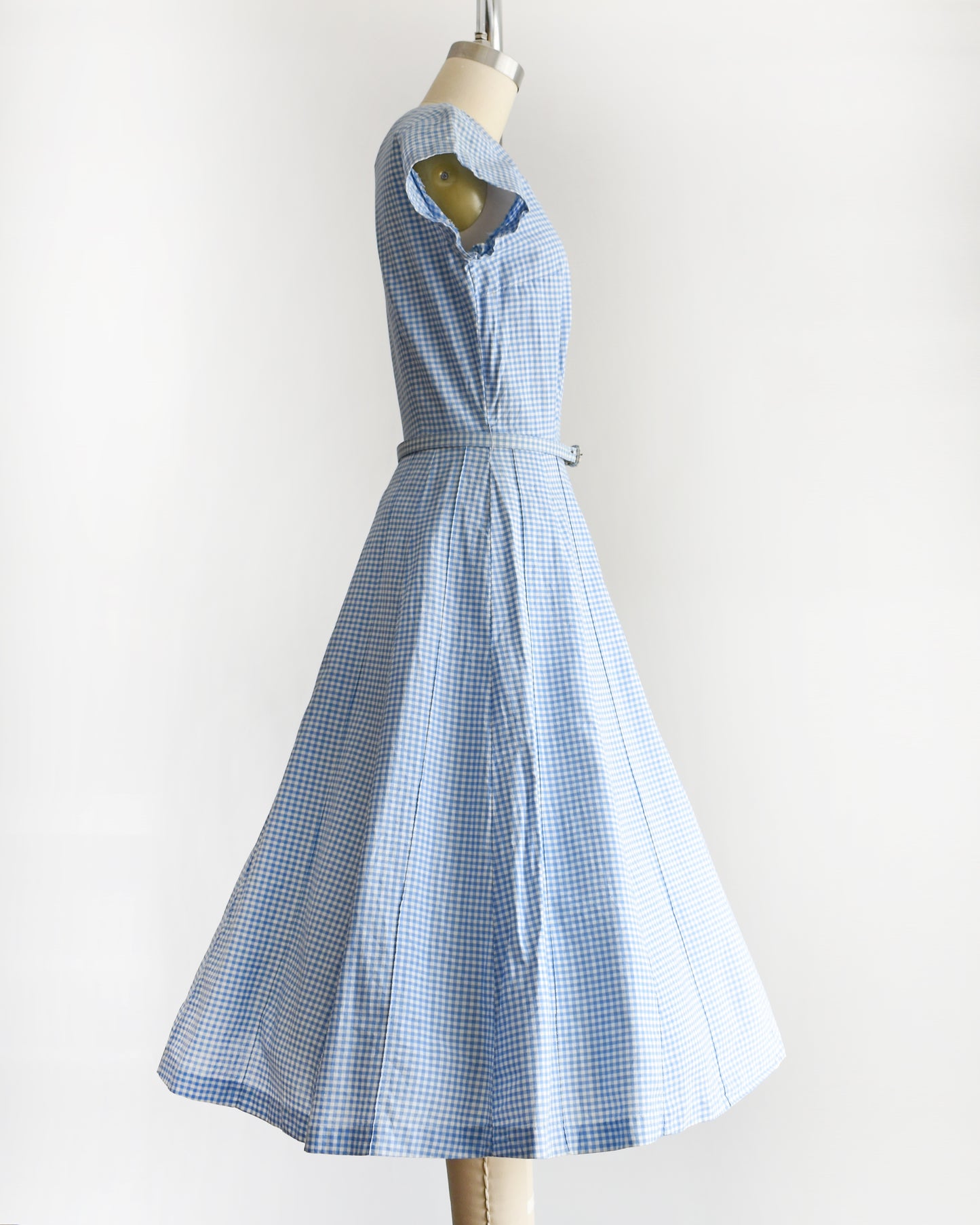 side view of a vintage 1950s blue and white gingham dress on a mannequin against a white background