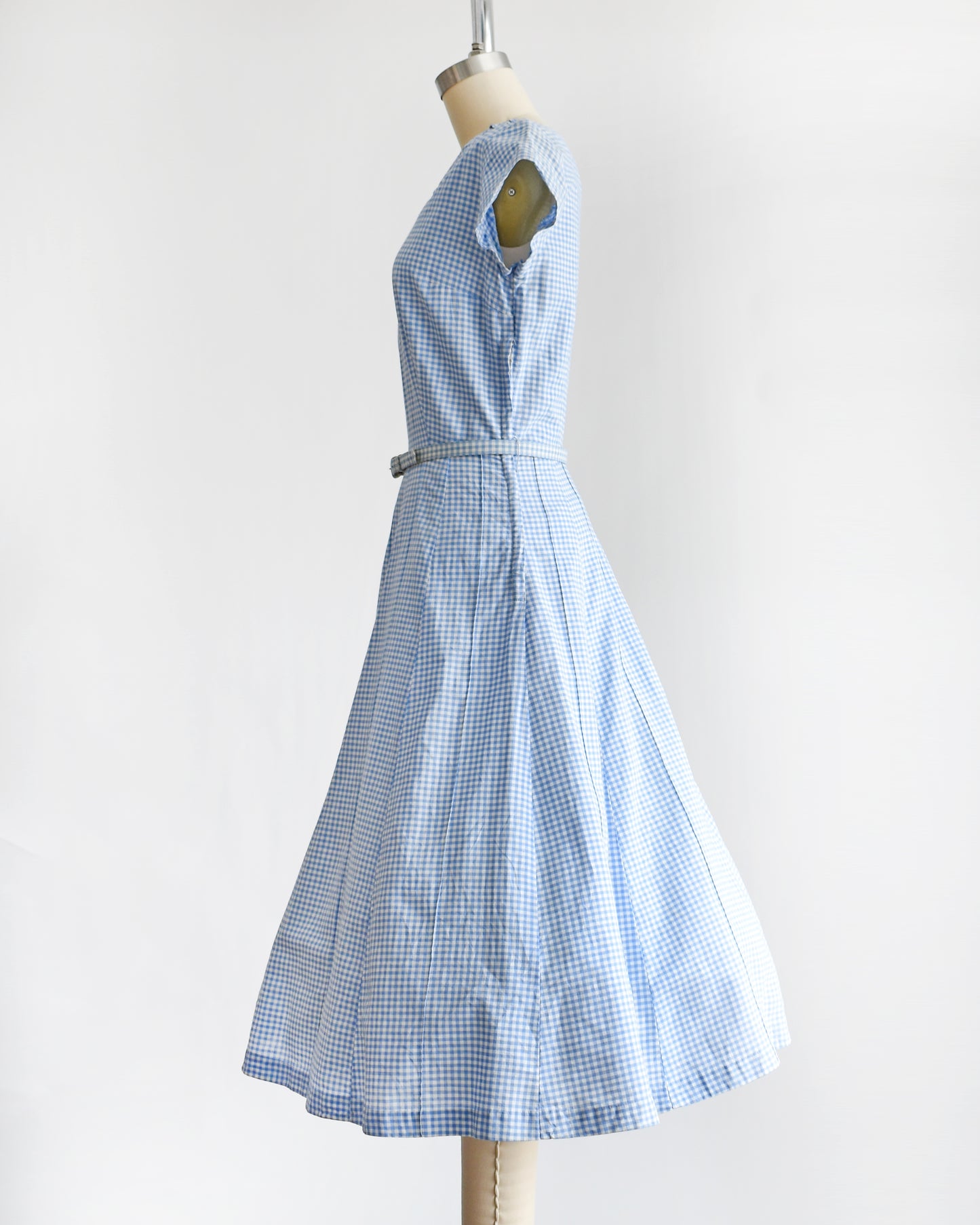 side view of a vintage 1950s blue and white gingham dress on a mannequin against a white background