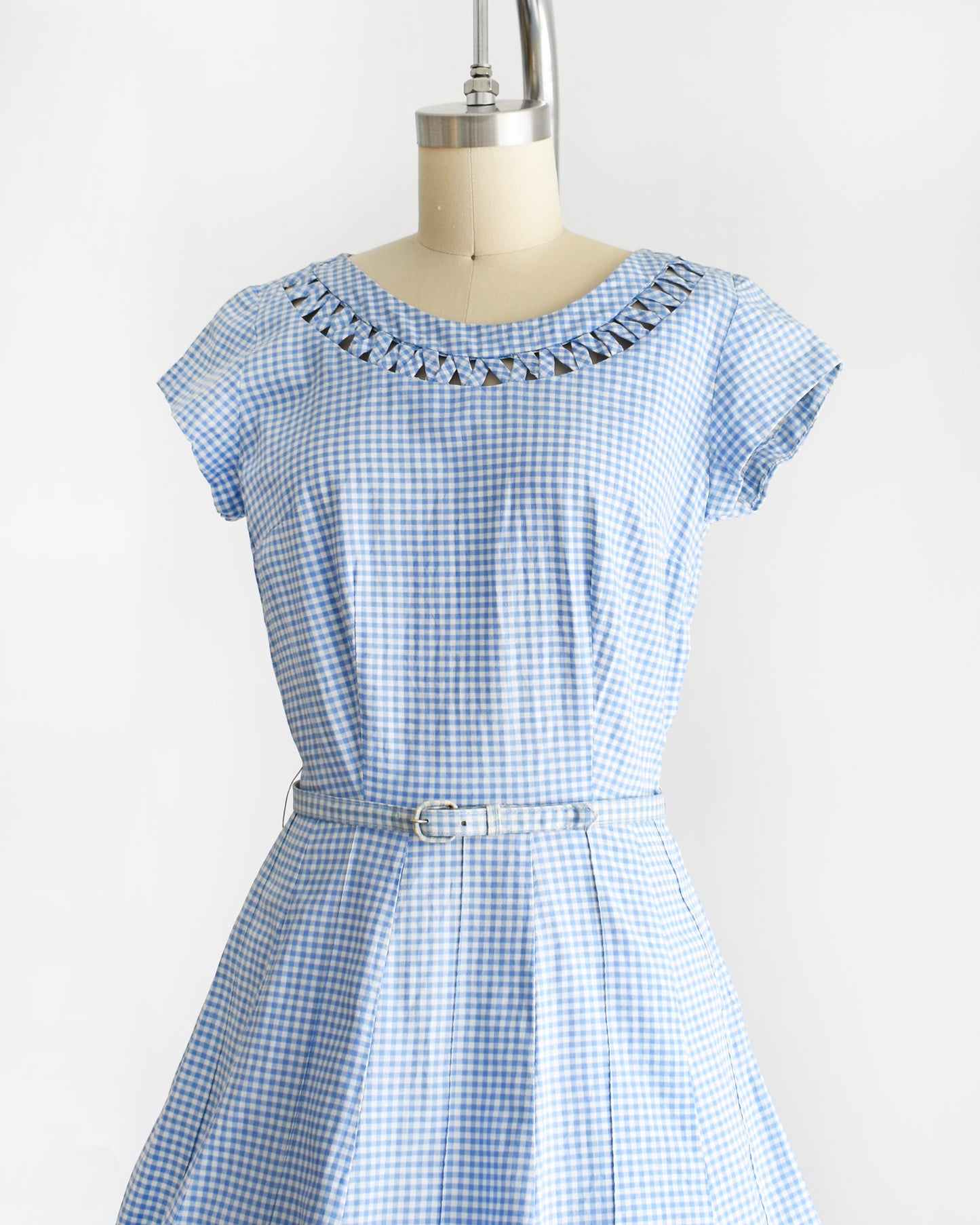 side front view of a vintage 1950s blue and white gingham dress on a mannequin against a white background