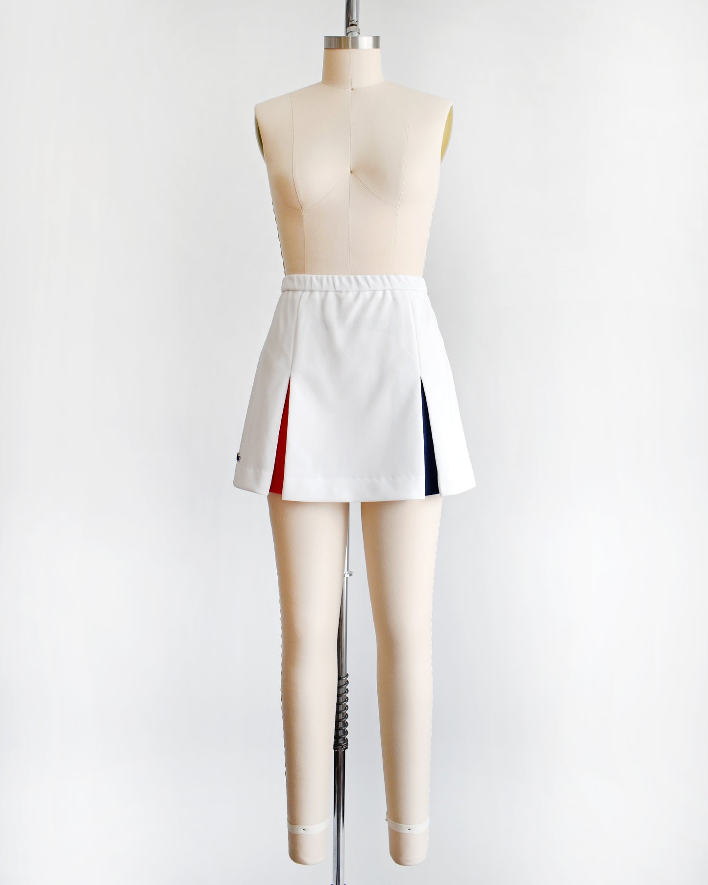 a vintage 1970s Lacoste Haymaker skirt with red and blue accented pleats on a mannequin against a white background