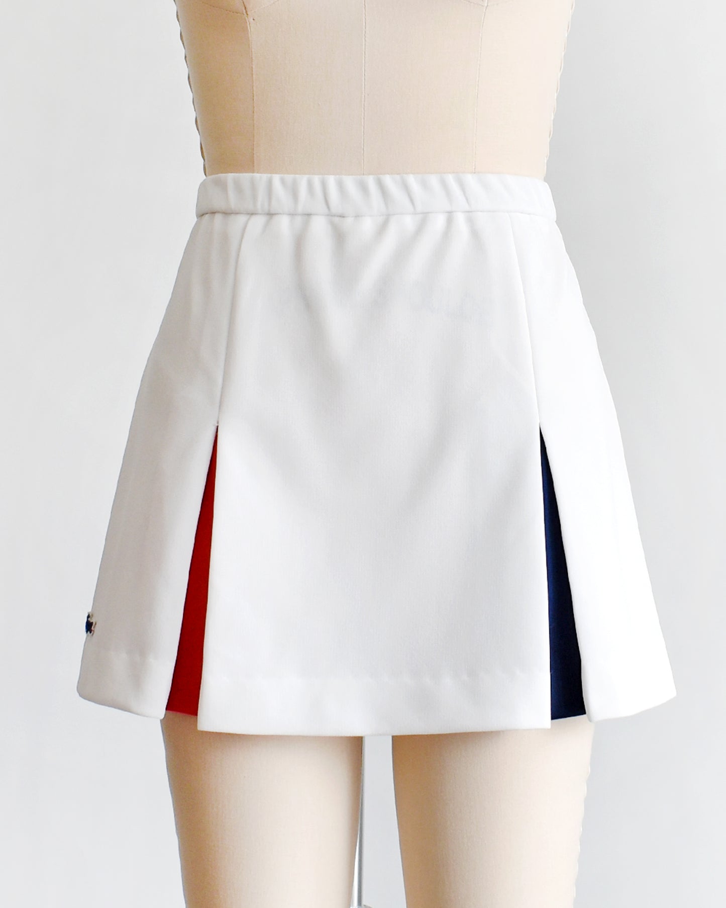 a vintage 1970s Lacoste Haymaker skirt with red and blue accented pleats on a mannequin against a white background