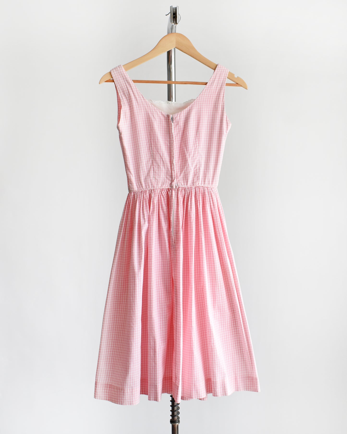back view of a vintage 1950s pink and white gingham dress on a mannequin against a white background
