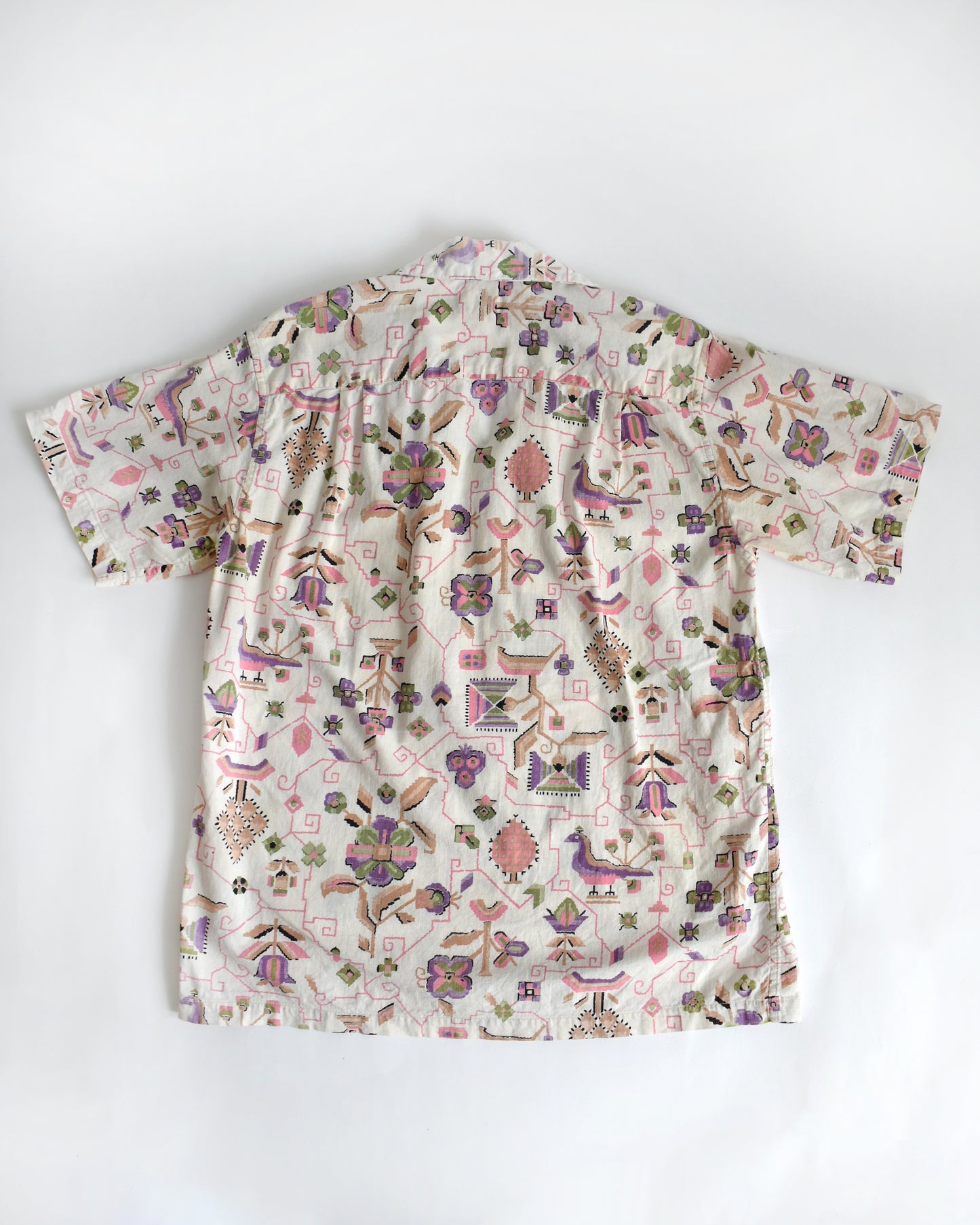 back view of a vintage 1950s Tiana Pittelle short-sleeve Hawaiian aloha shirt with a colorful pattern on a white background