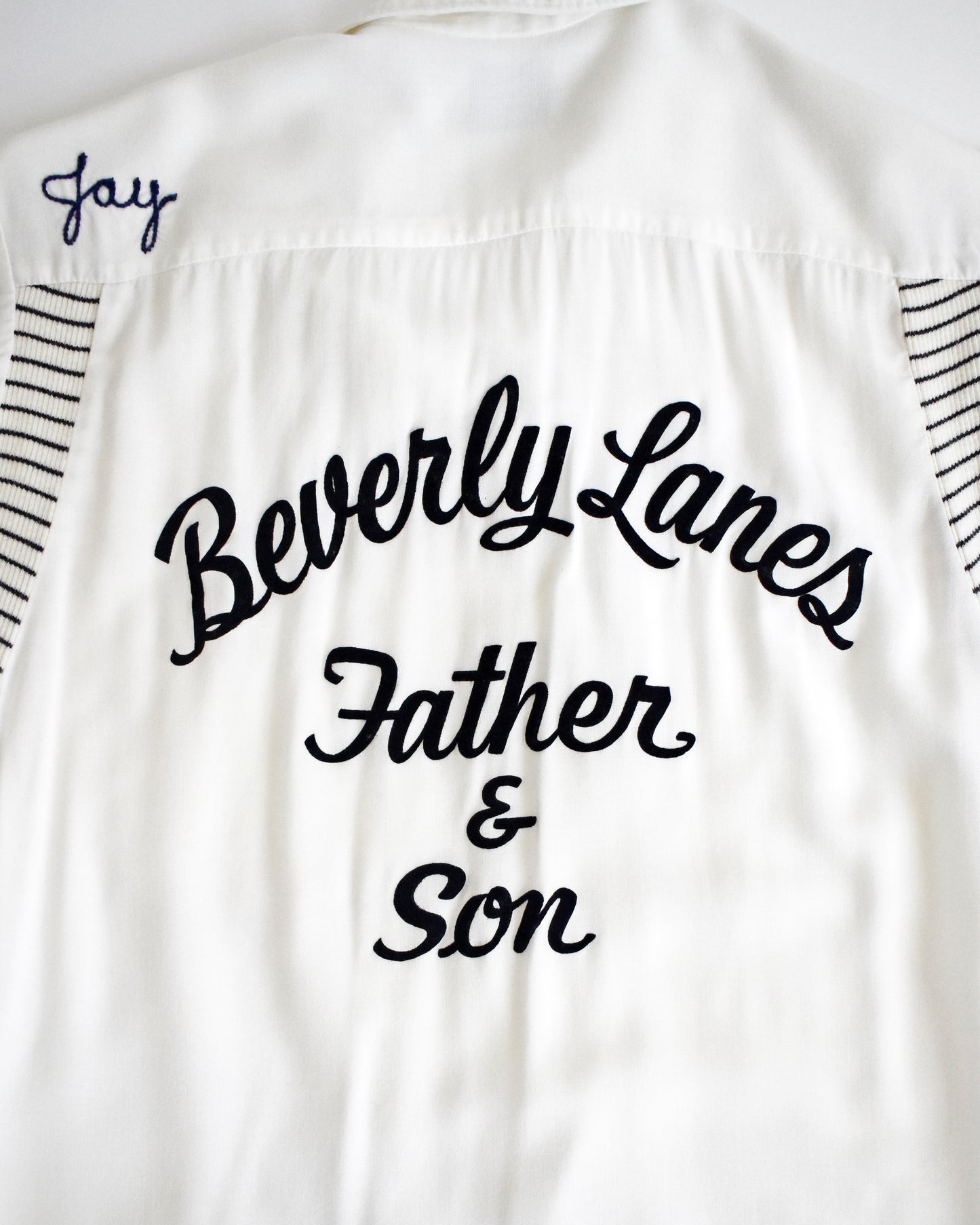 close up of the back of a vintage 1950s Olympian bowling white shirt with 'Beverly Lanes Father & Son' text on a white background