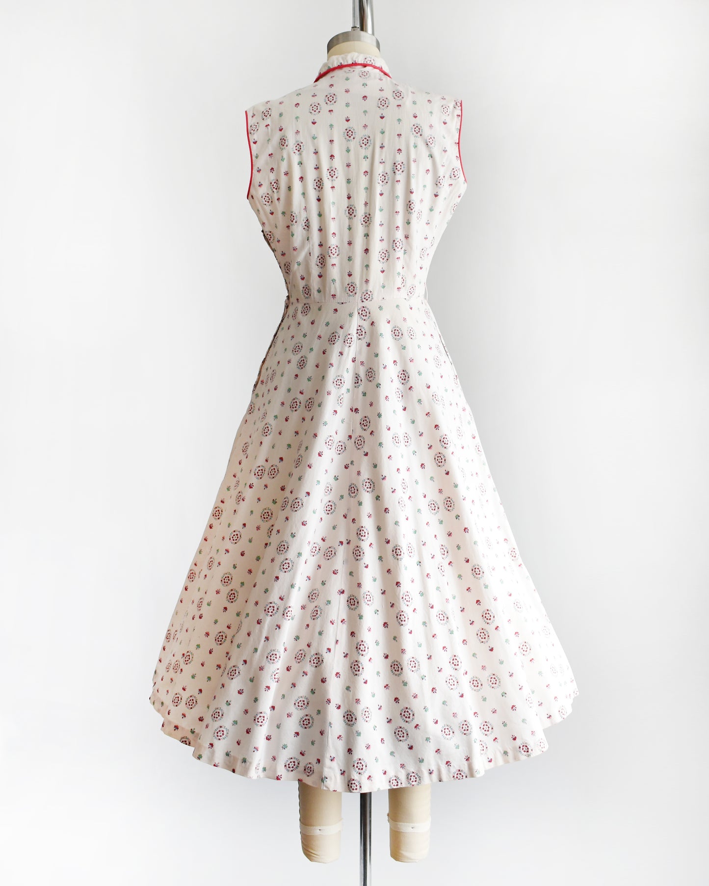 back view of a vintage 1950s floral dress on a mannequin against a white background