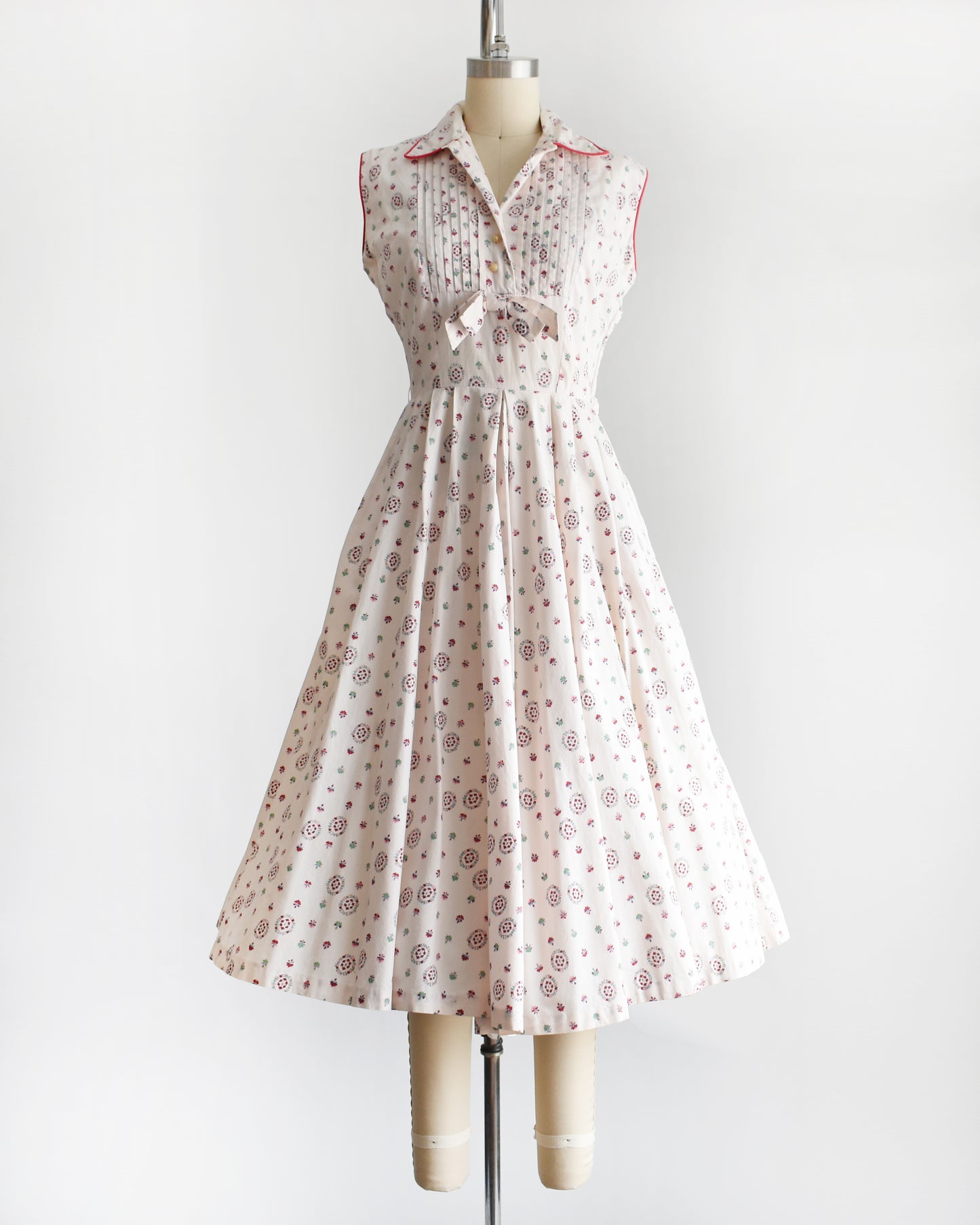a vintage 1950s floral dress on a mannequin against a white background. the dress has the top button unbuttoned
