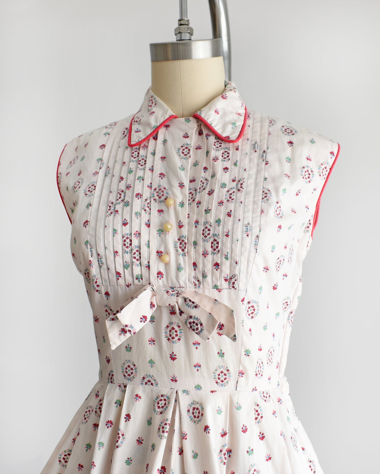 side front view of a vintage 1950s floral dress on a mannequin against a white background