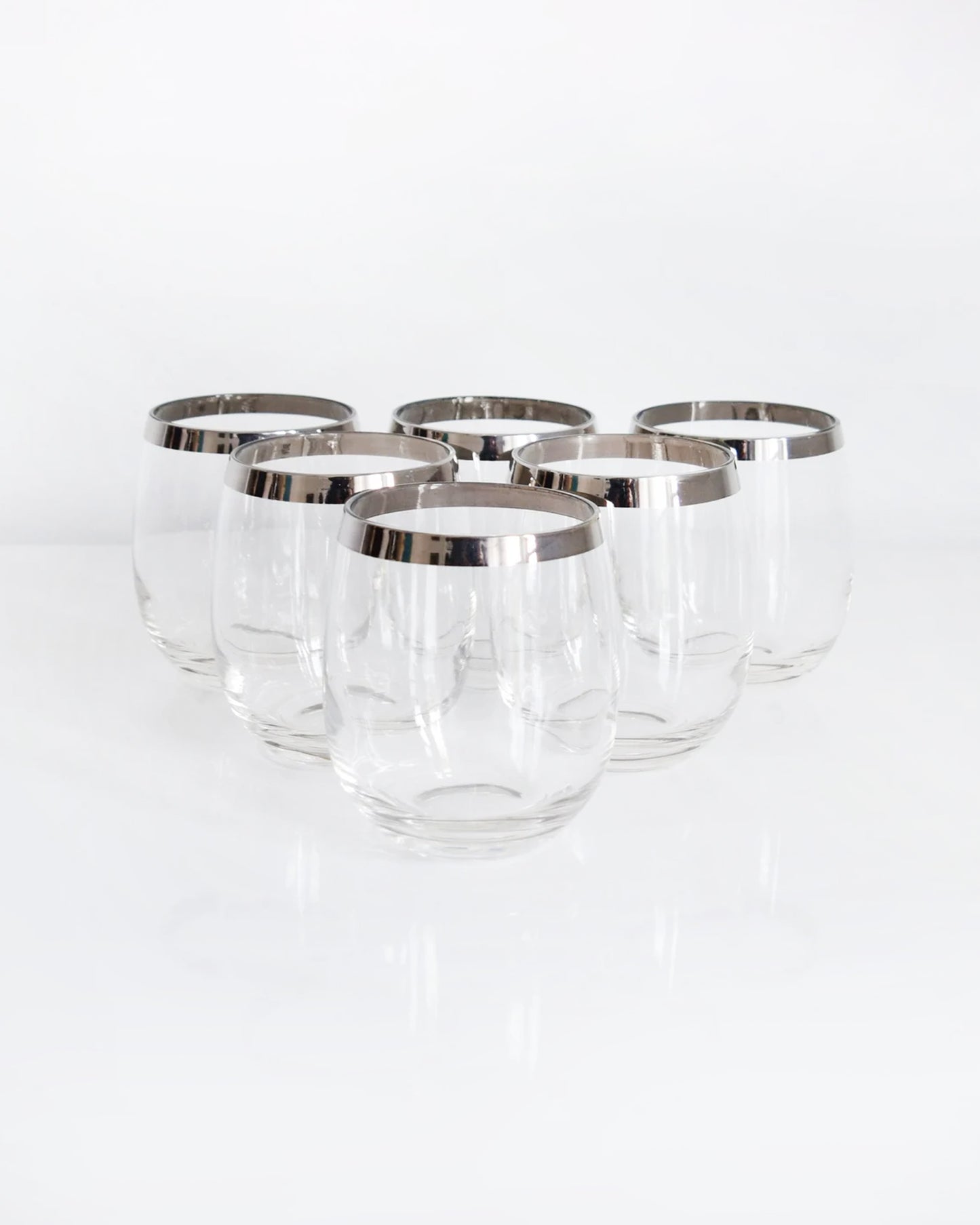 A set of 6 vintage 60s sliver rim tumblers that have an elongated roly poly shape