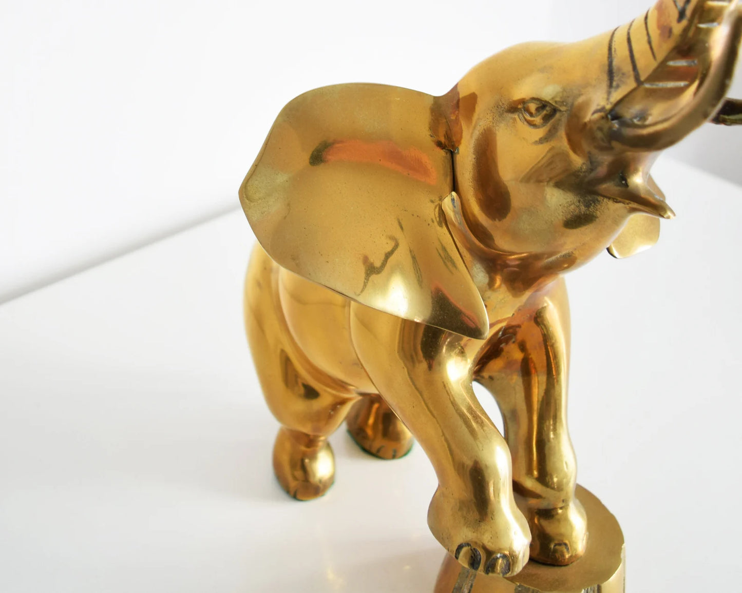 Close up of the brass elephant's side of face and ear, which shows a light spot on the ear