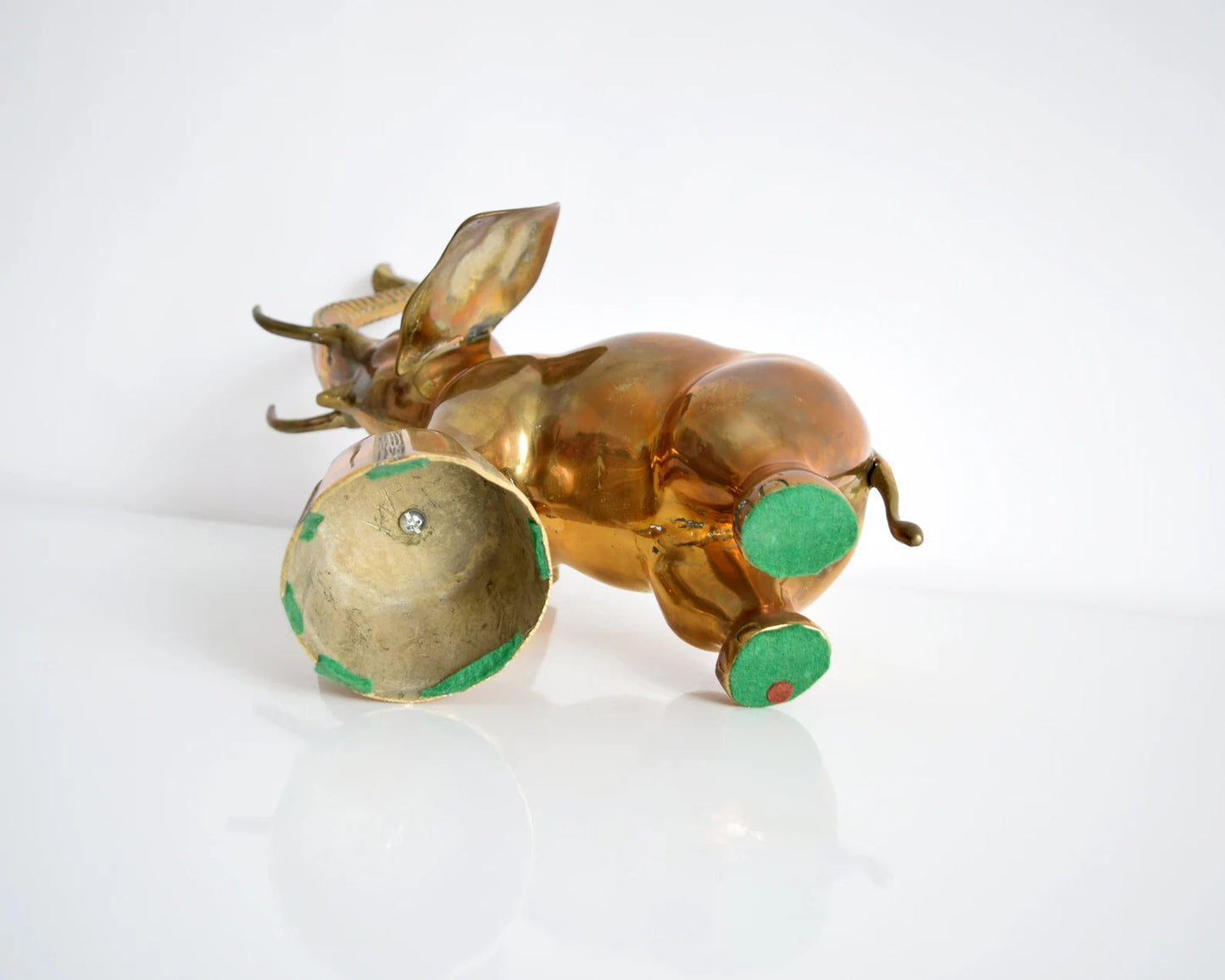 Bottom view of the brass elephant which shows green felt on the two back feet and some on the platform