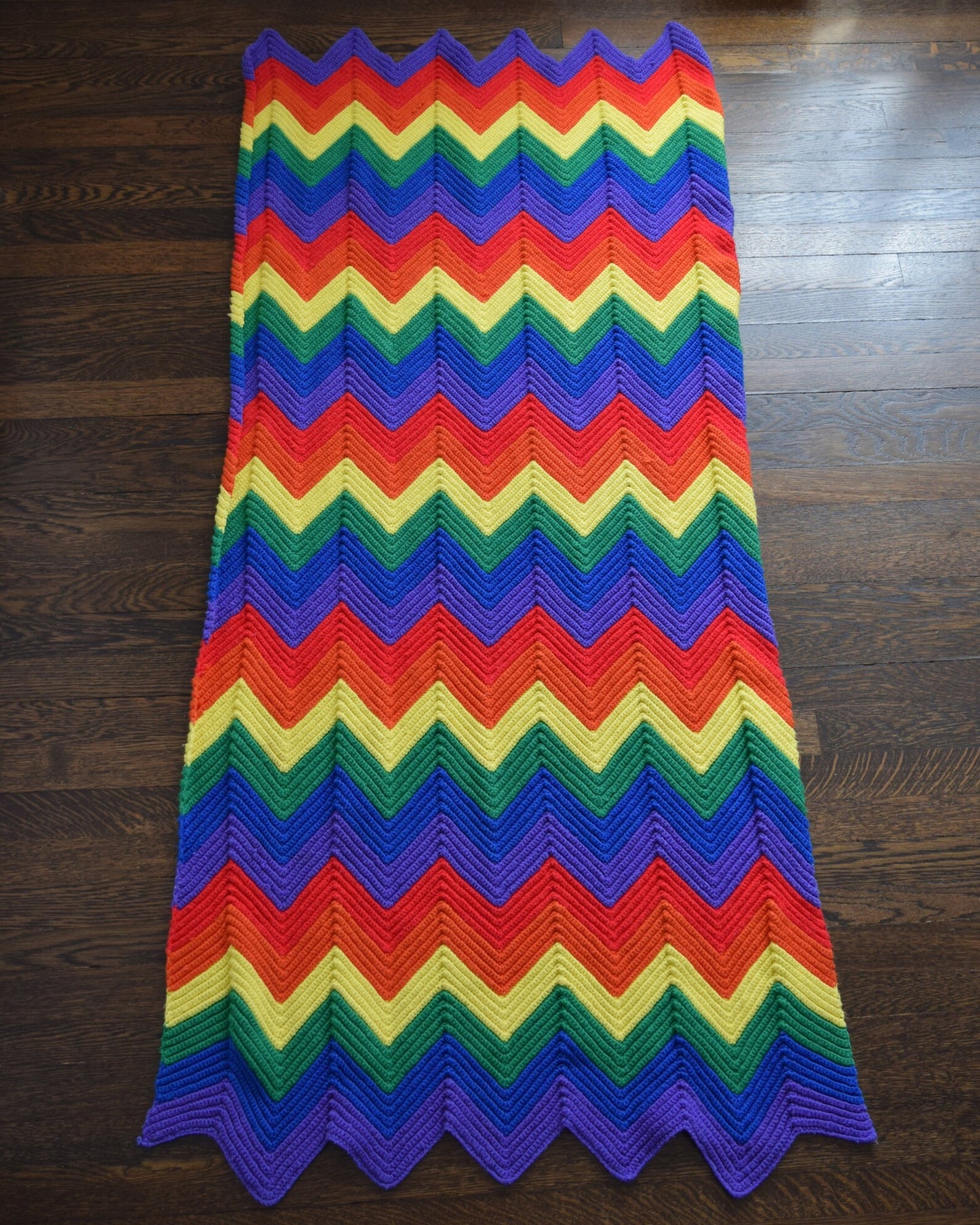 A vintage rainbow chevron striped blanket laid out on a wood floor