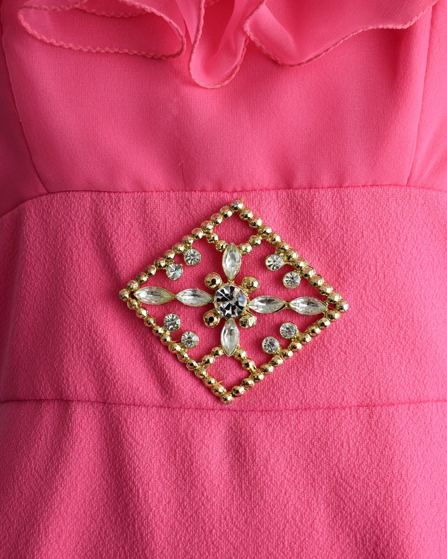 A close up of the gold tone rhinestone brooch at the waist