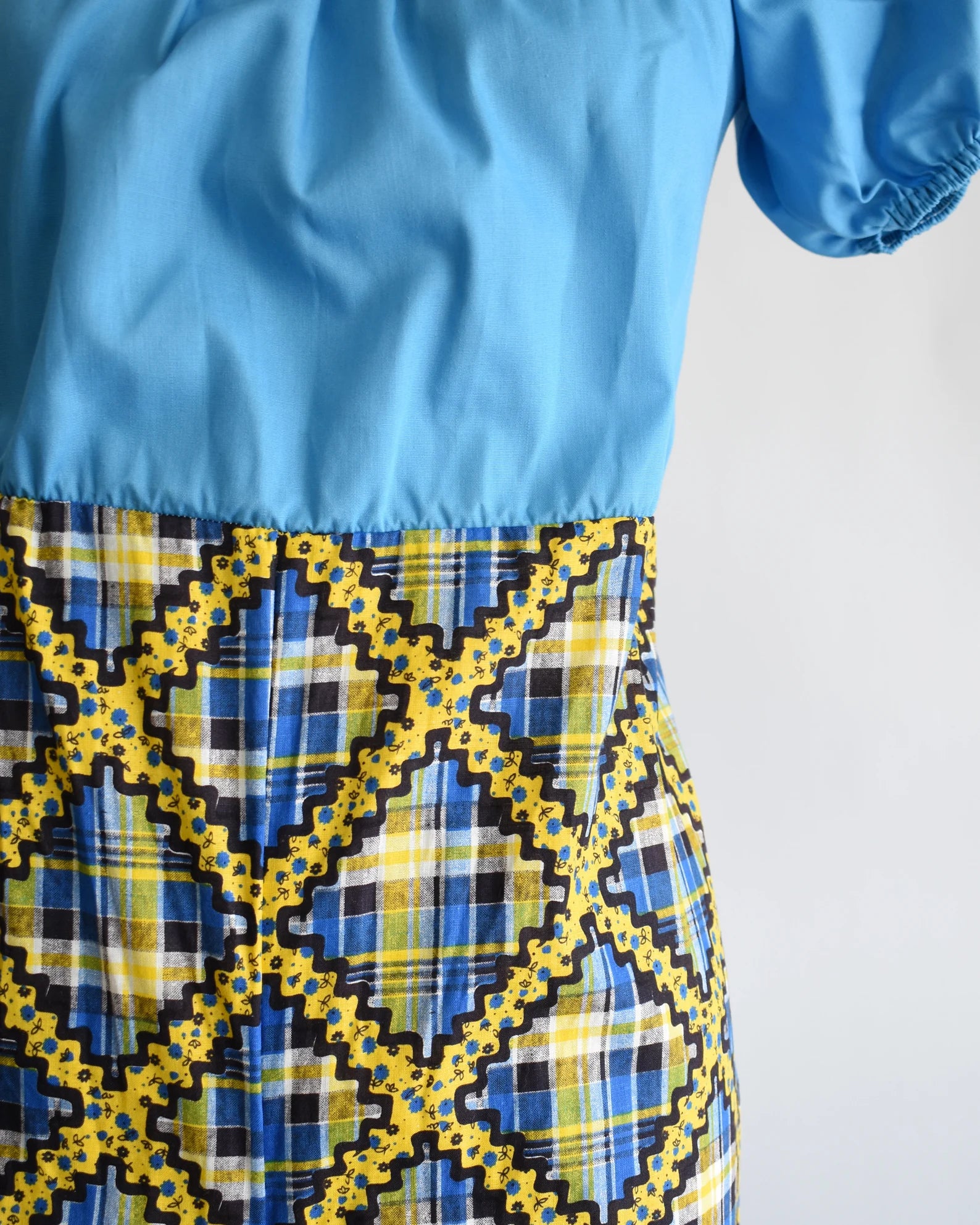 Close up of the waistline with the blue bodice on top and plaid pants underneath.