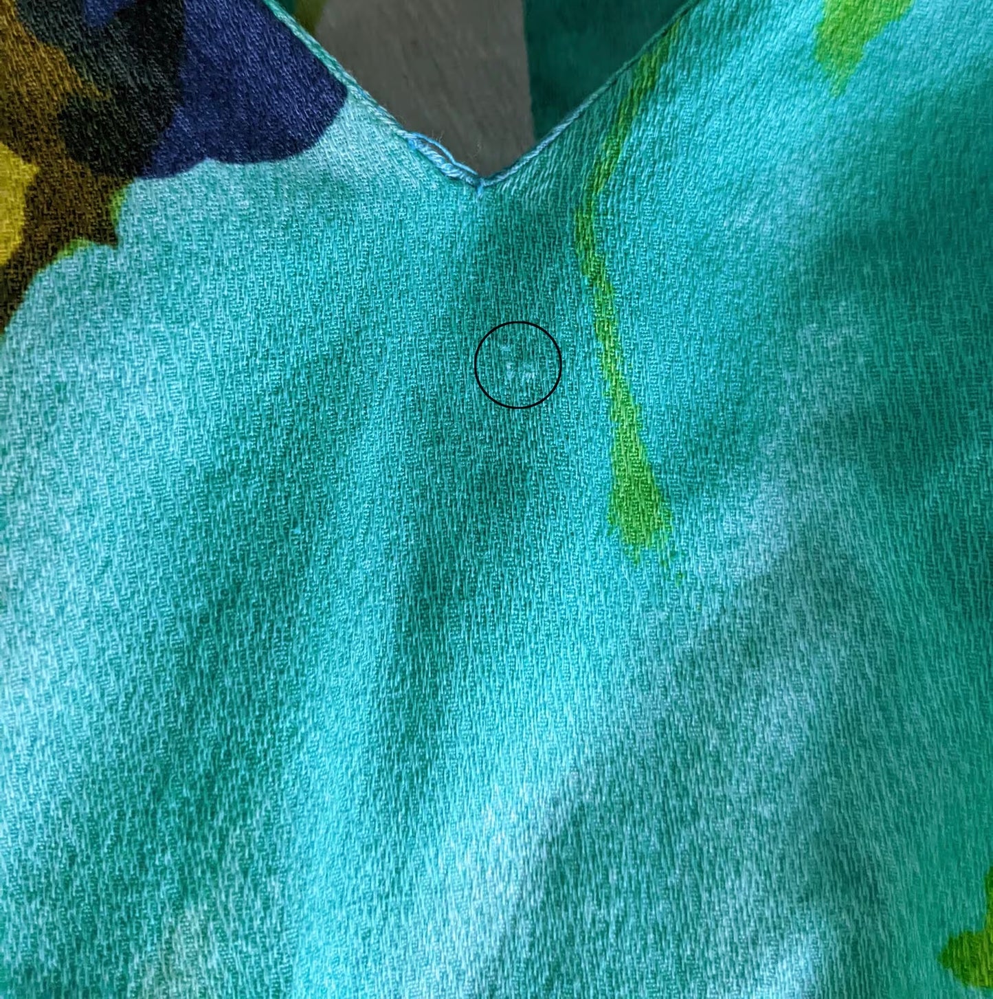 A very small spot under the front neckline where the fabric is frayed.