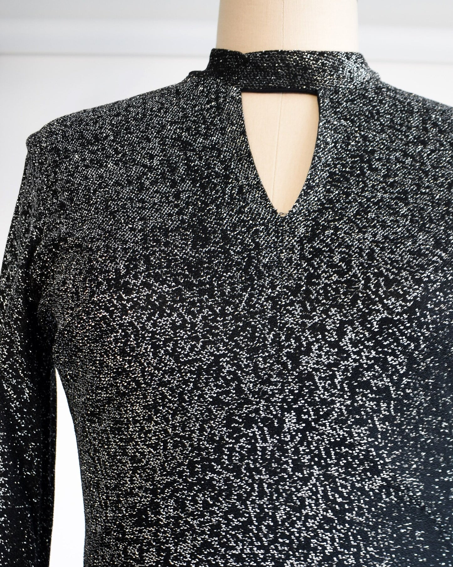 Close up of the bodice of the dress which shows the keyhole cutout under the neck and the black and silver sparkly fabric