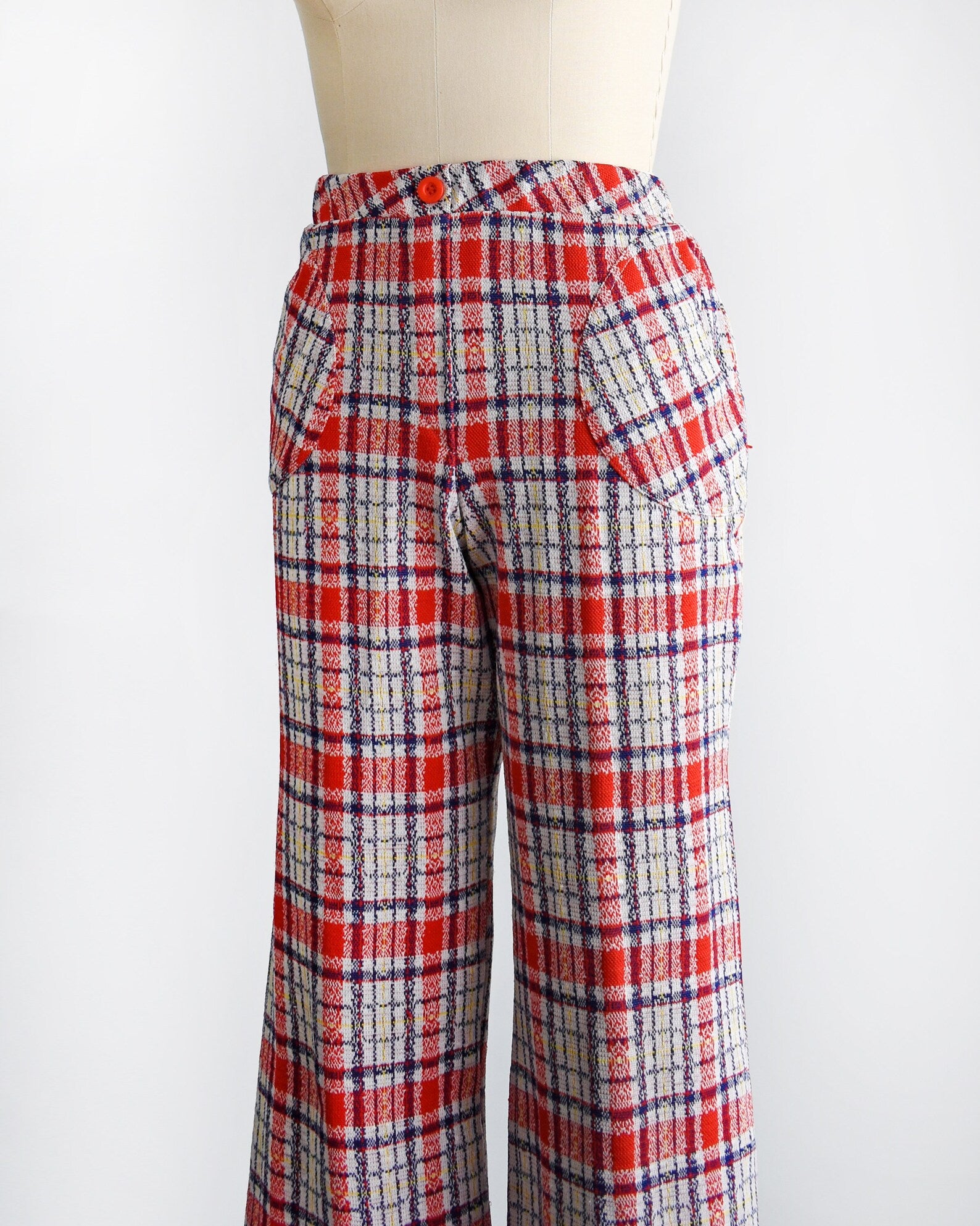 Side front view of  vintage pair of 70s red white and blue plaid wide leg pants on a dress form.