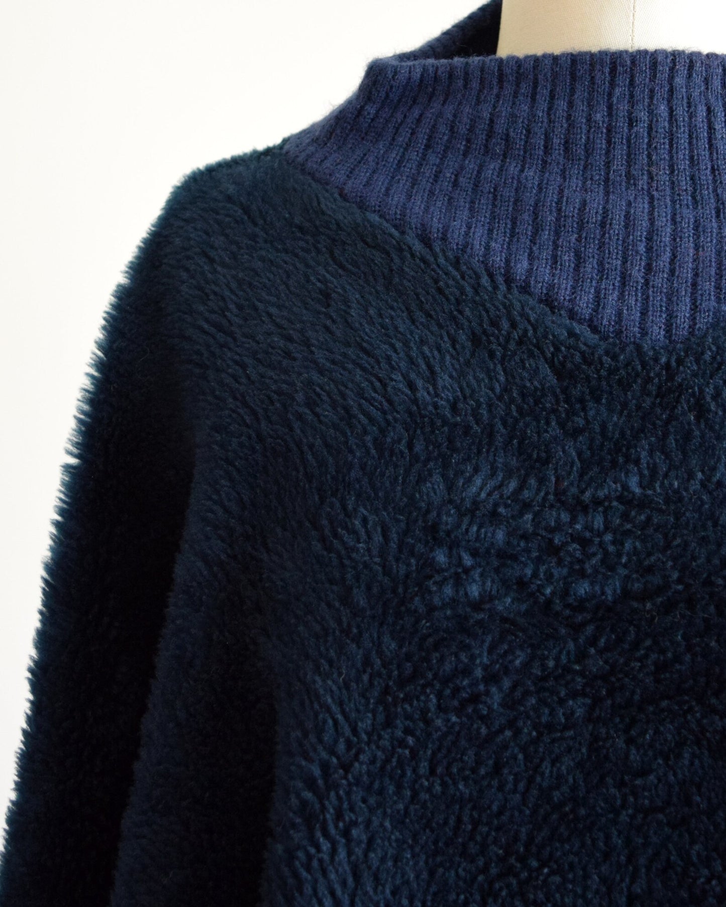 Close up of a vintage 70s dark blue fuzzy fleece poncho with a ribbed collar.