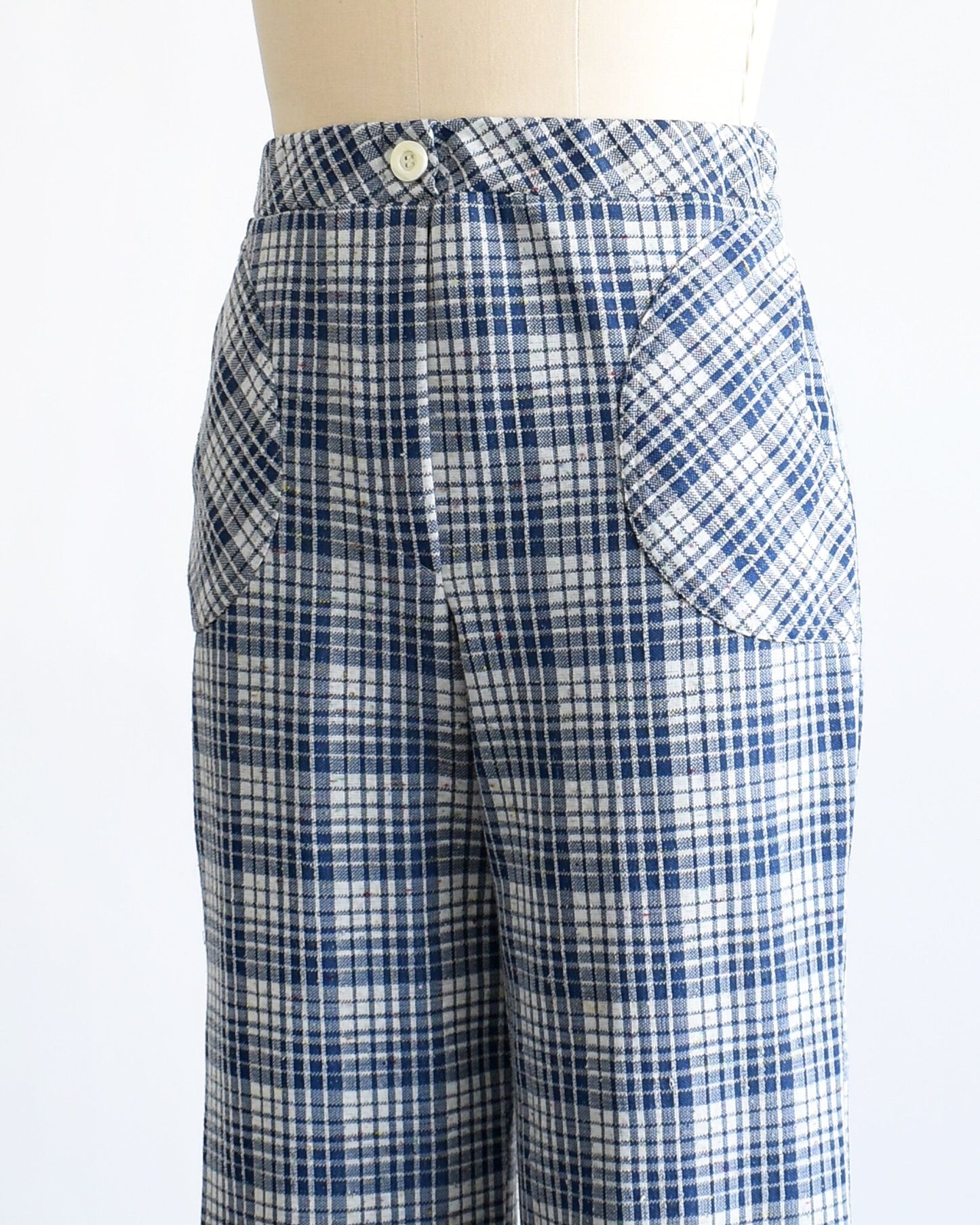 Close up side view of a vintage pair of 70s blue and white plaid wide leg pants on a dress form.